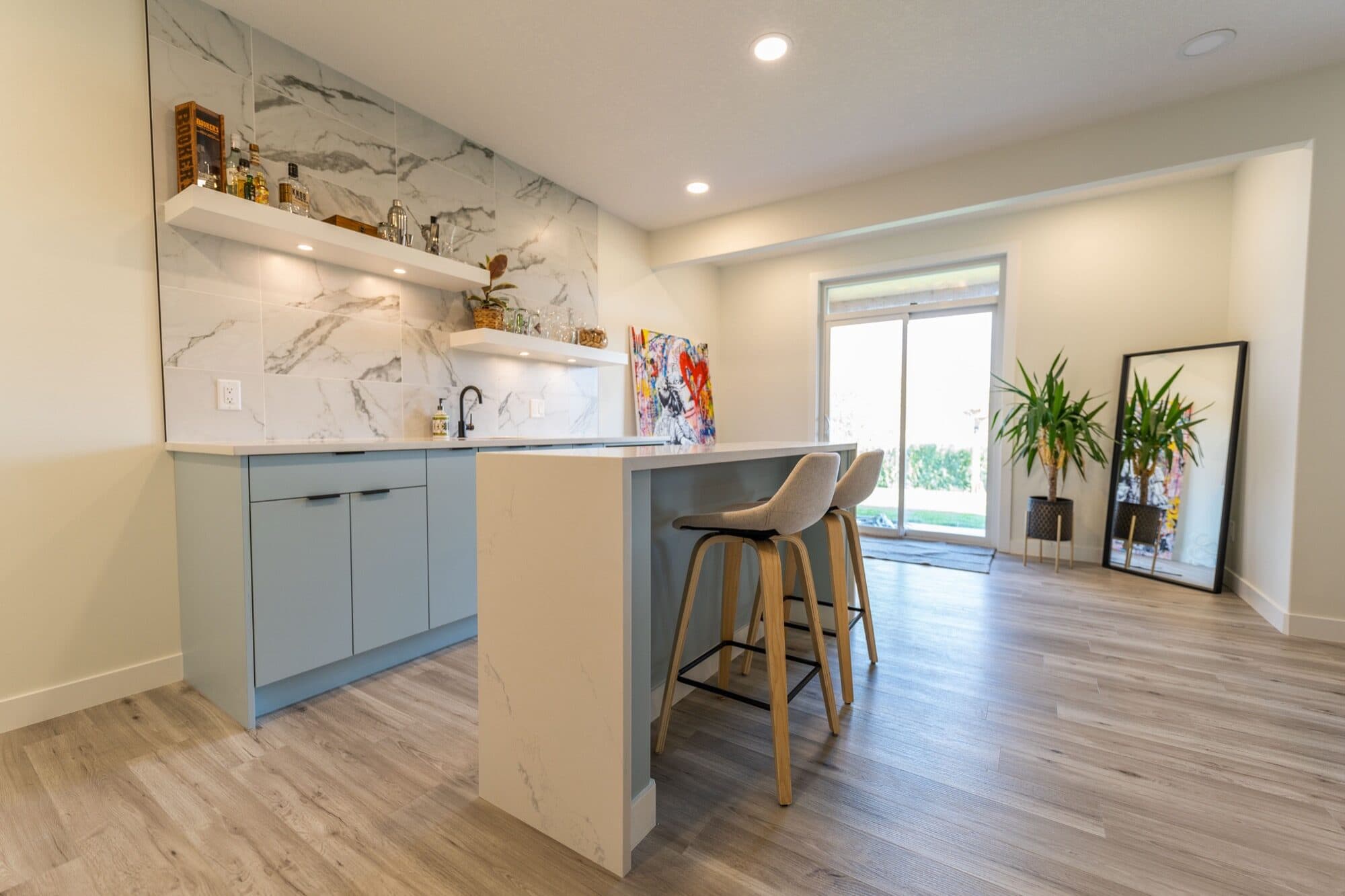 Basement wet bar with blue cabinets and marble backsplash, bar angle
