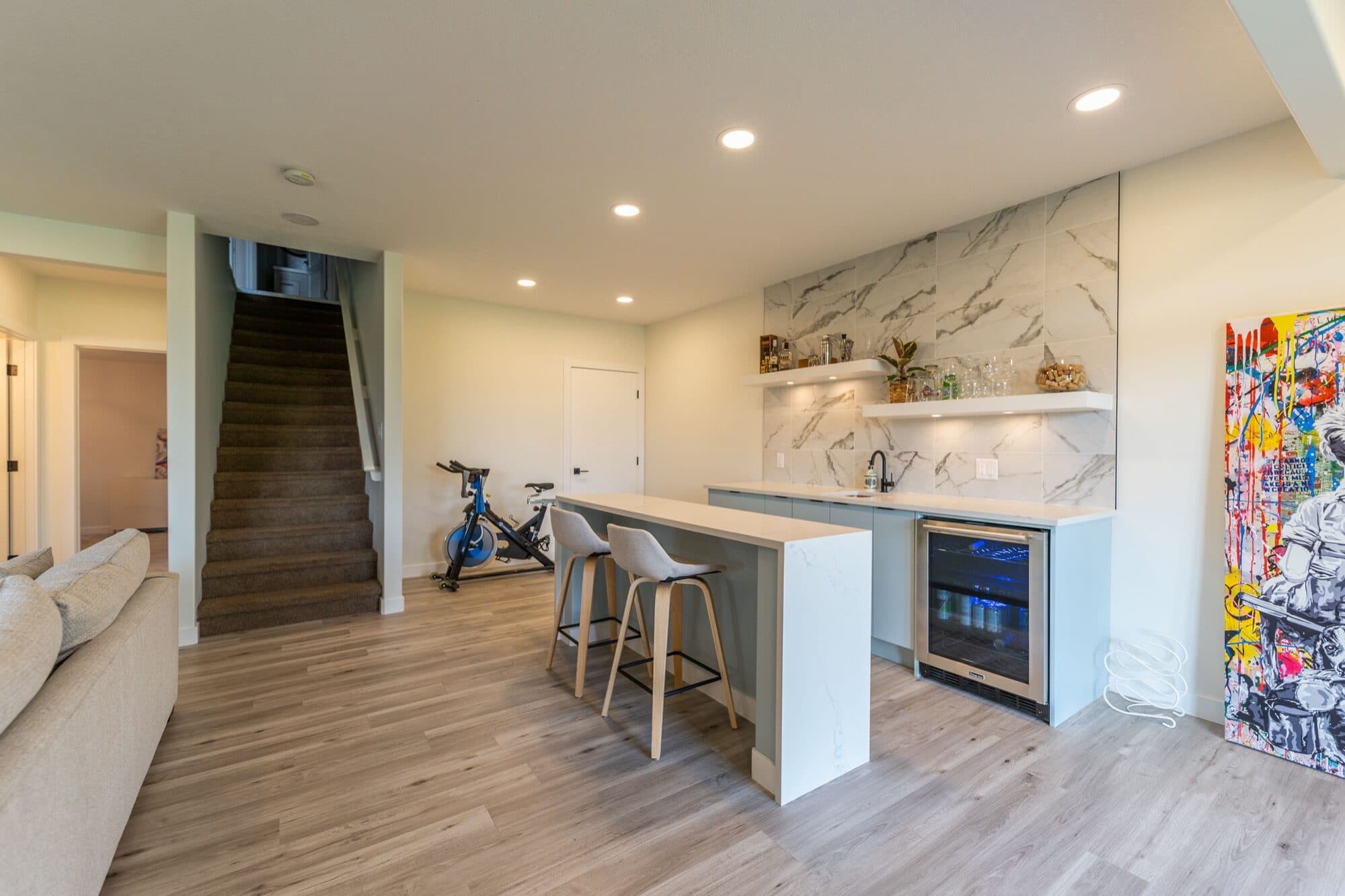 Basement wet bar with marble backsplash, wine fridge and bar stools