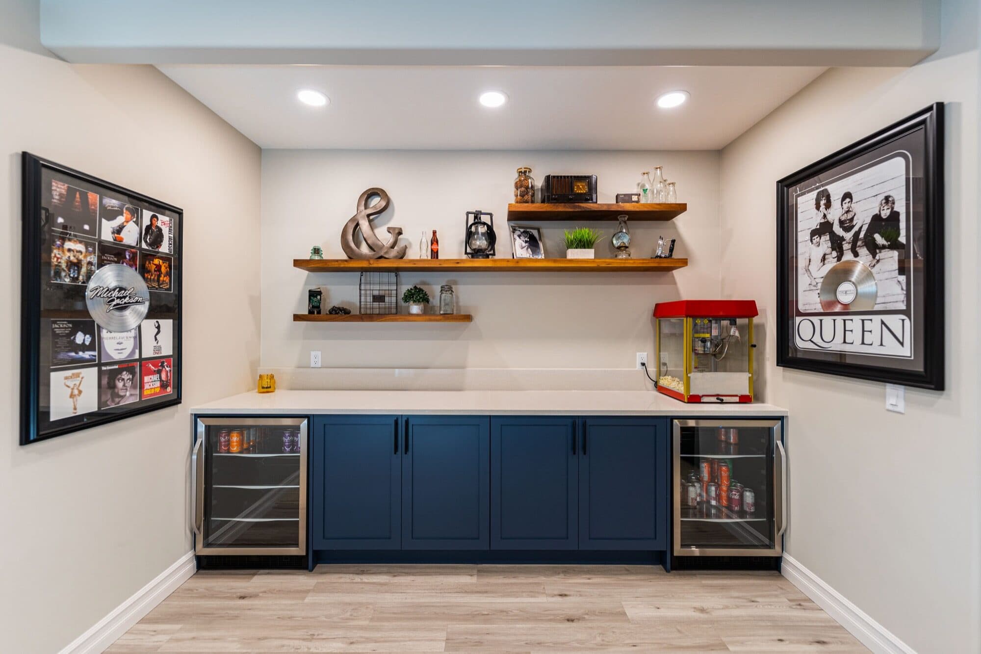 Basement bar with navy cabinets, dual beverage fridges and popcorn machine