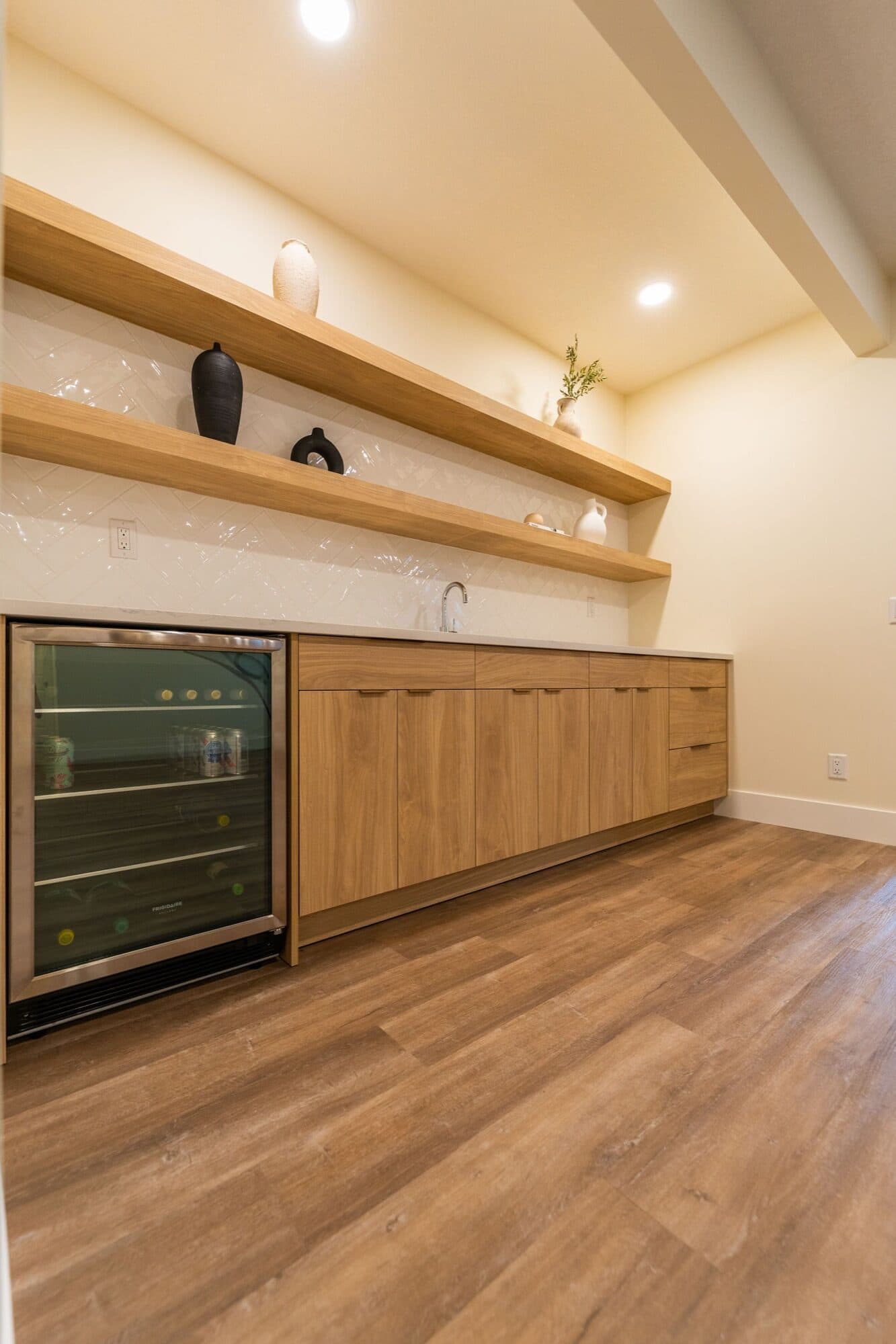 Basement bar with oak cabinets, wine fridge and open shelves, angled