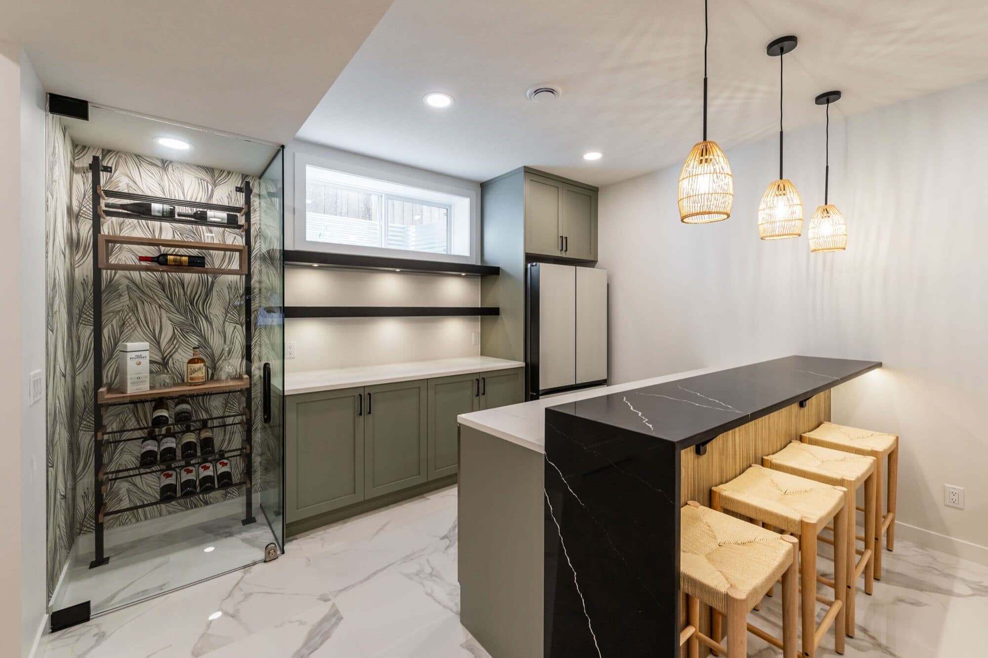 Basement bar with sage cabinets, rattan stools and glass wine room
