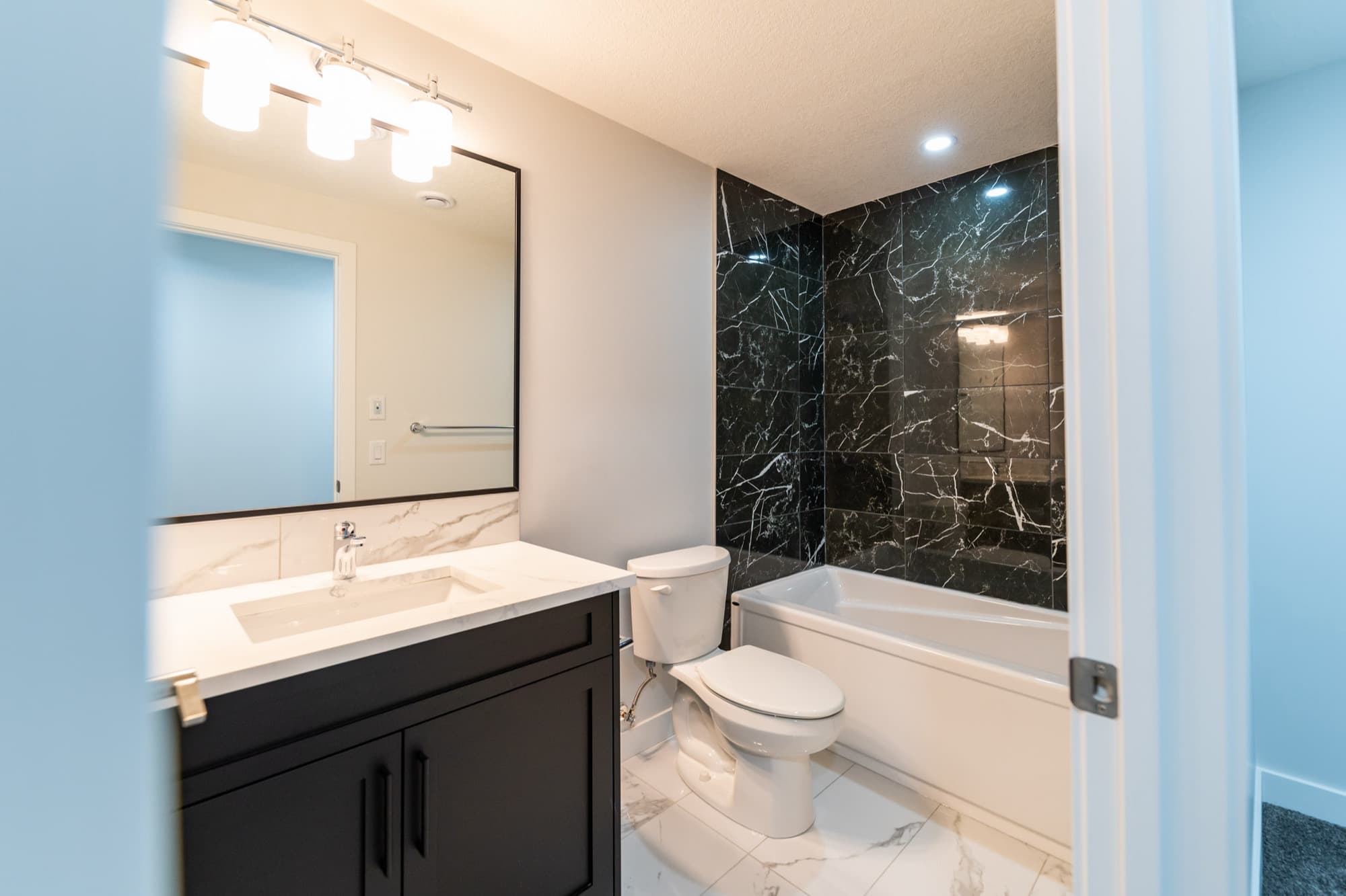 Basement bathroom with black marble tub surround and white marble vanity