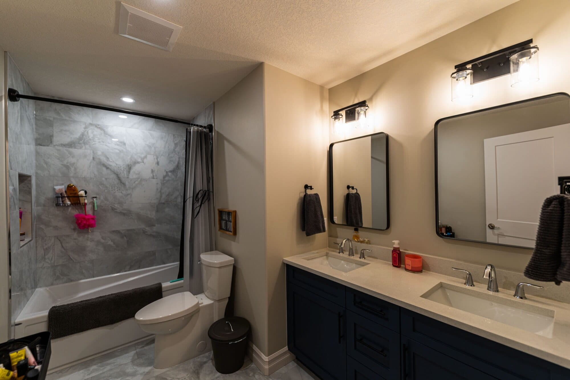 Basement bathroom with grey marble tub and double navy vanity
