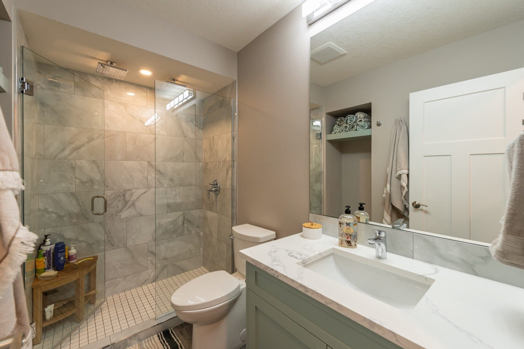 Basement bathroom with marble glass shower and sage green vanity