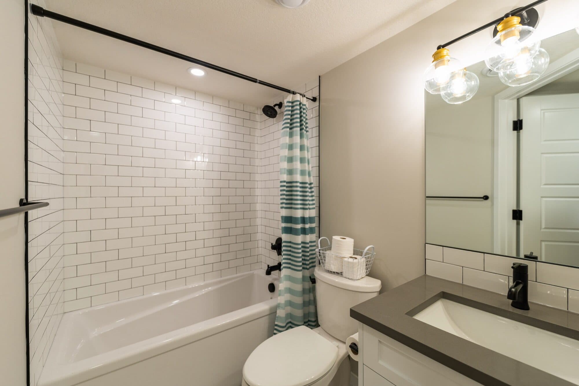 Basement bathroom with white subway tile tub and black matte hardware
