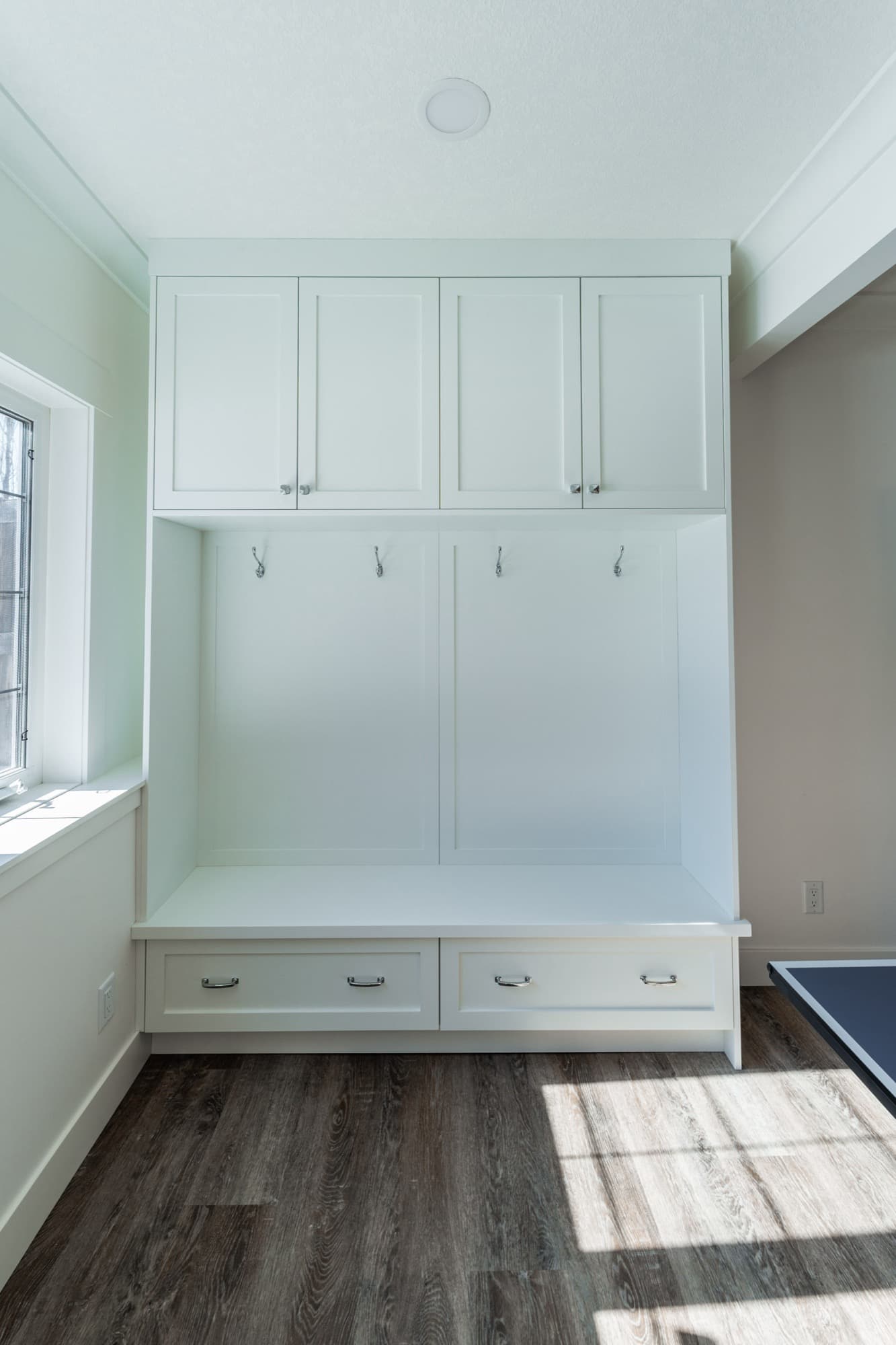 Basement built-in mudroom with white lockers, bench and hooks