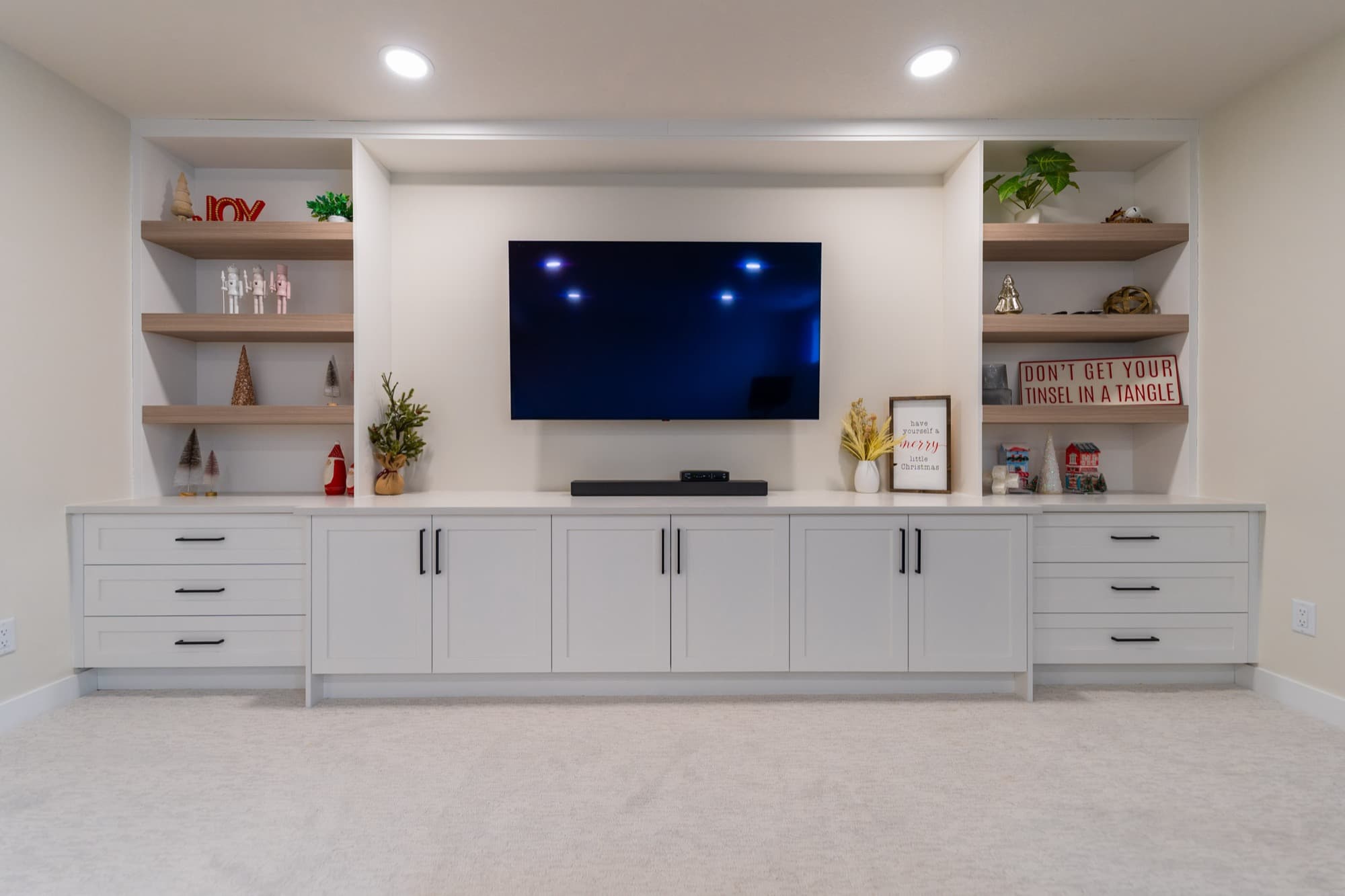 Basement built-in entertainment wall with white shaker cabinets and shelves
