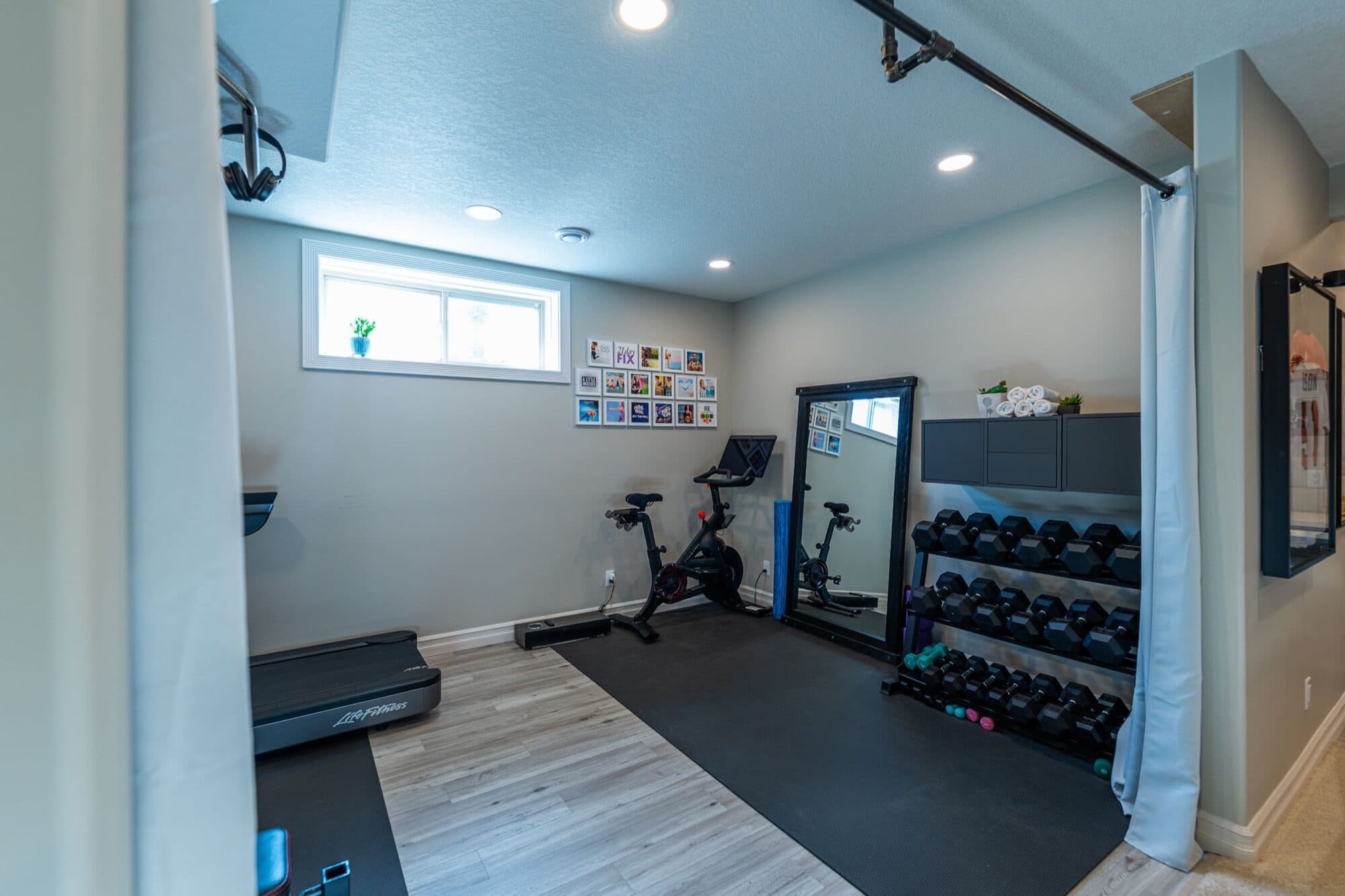 Basement gym with dumbbell rack, spin bike and curtain divider