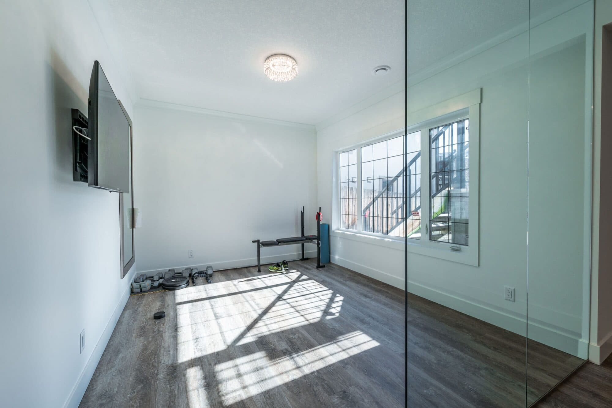 Basement gym with glass wall, weight bench and mirrors