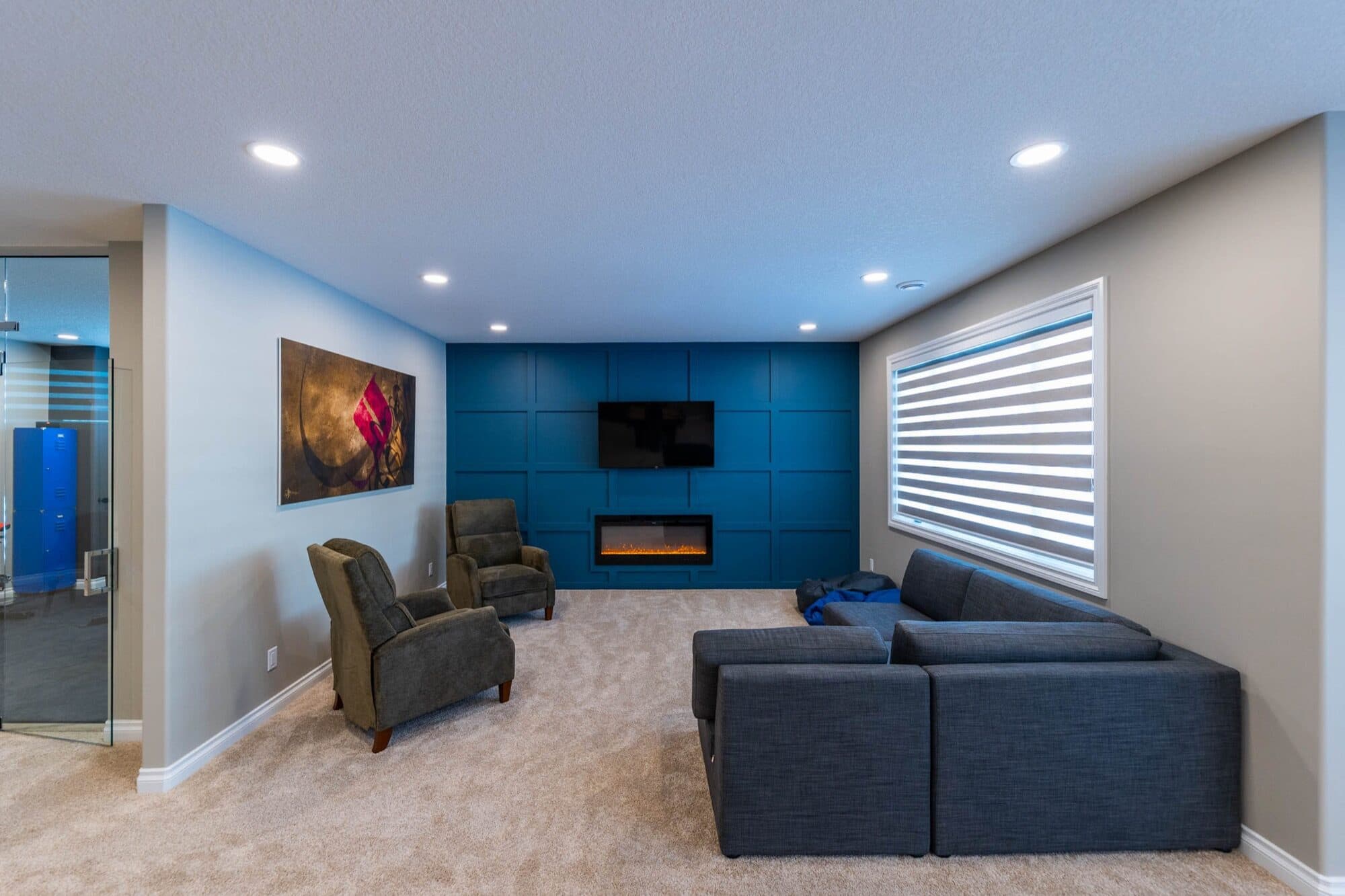 Basement rec room with blue accent wall, electric fireplace and sectional
