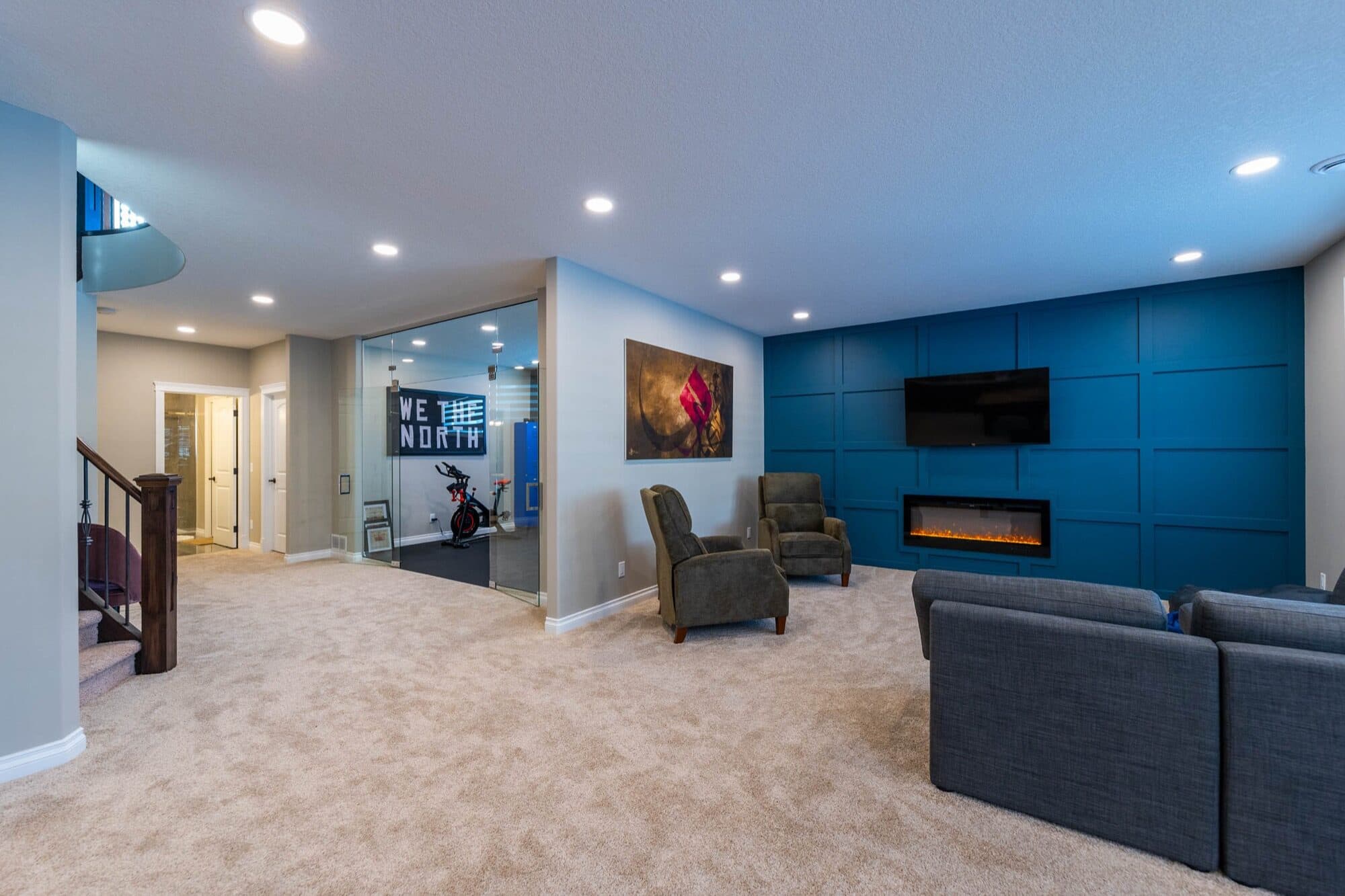 Basement rec room with blue accent wall and glass gym beyond