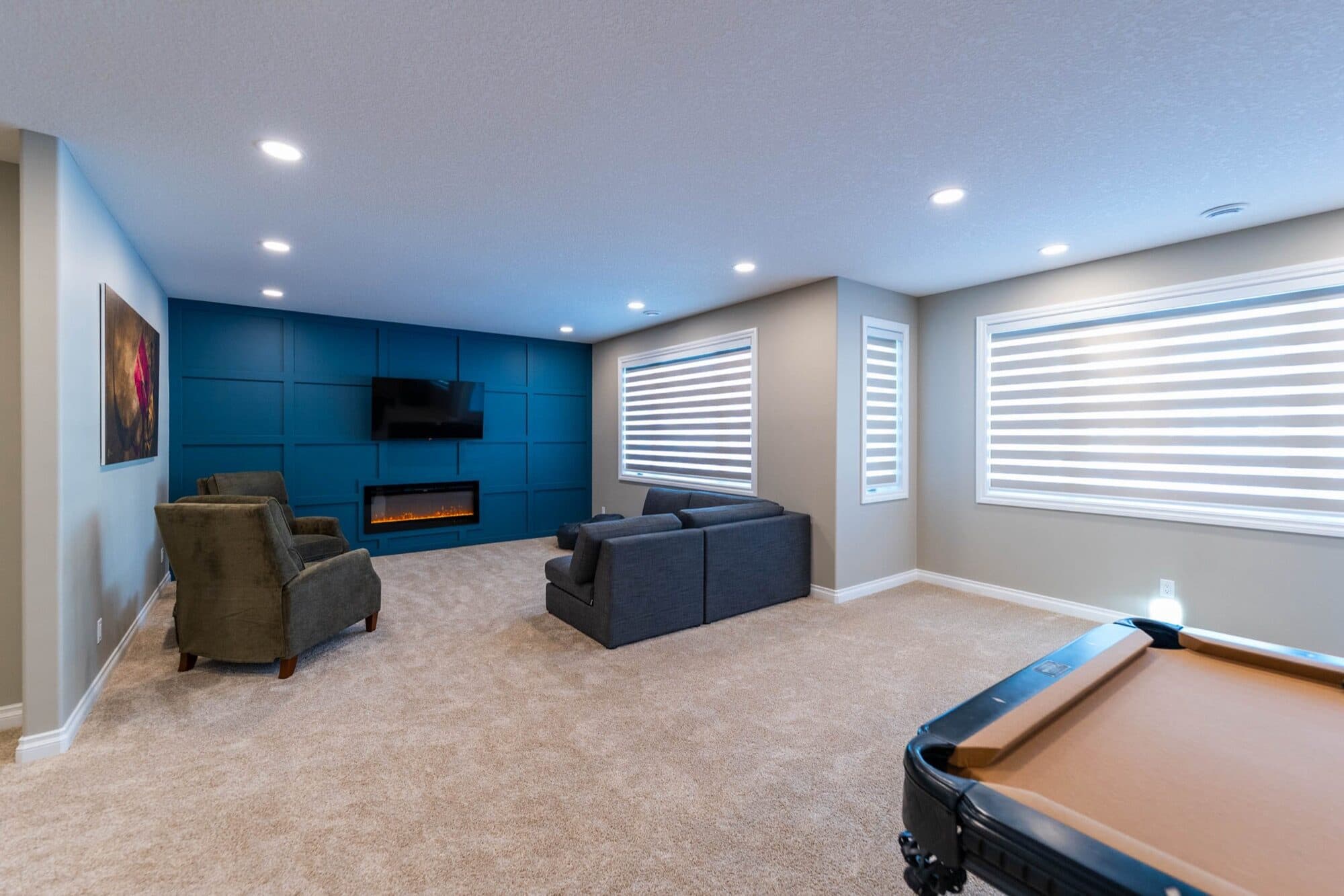 Basement rec room with blue accent wall and pool table, wide angle