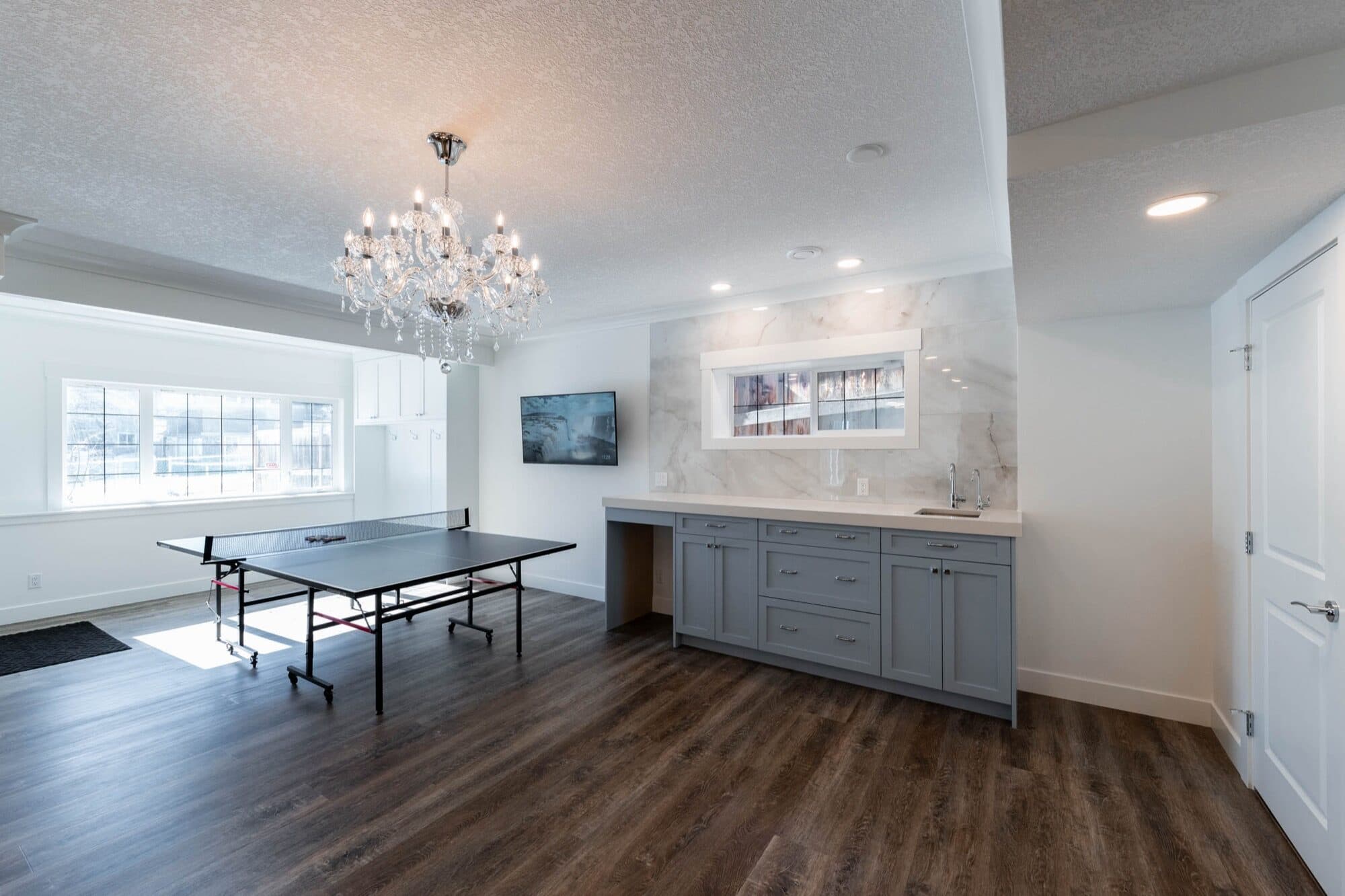 Basement rec room with crystal chandelier, ping pong table and bar