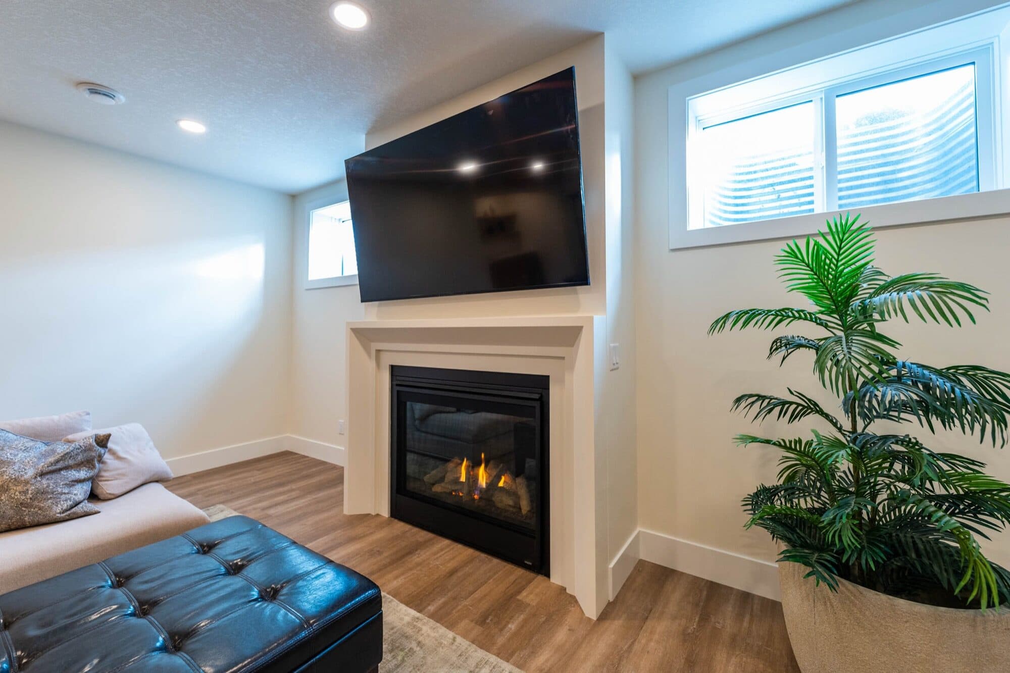 Basement rec room with gas fireplace, TV wall and leather ottoman