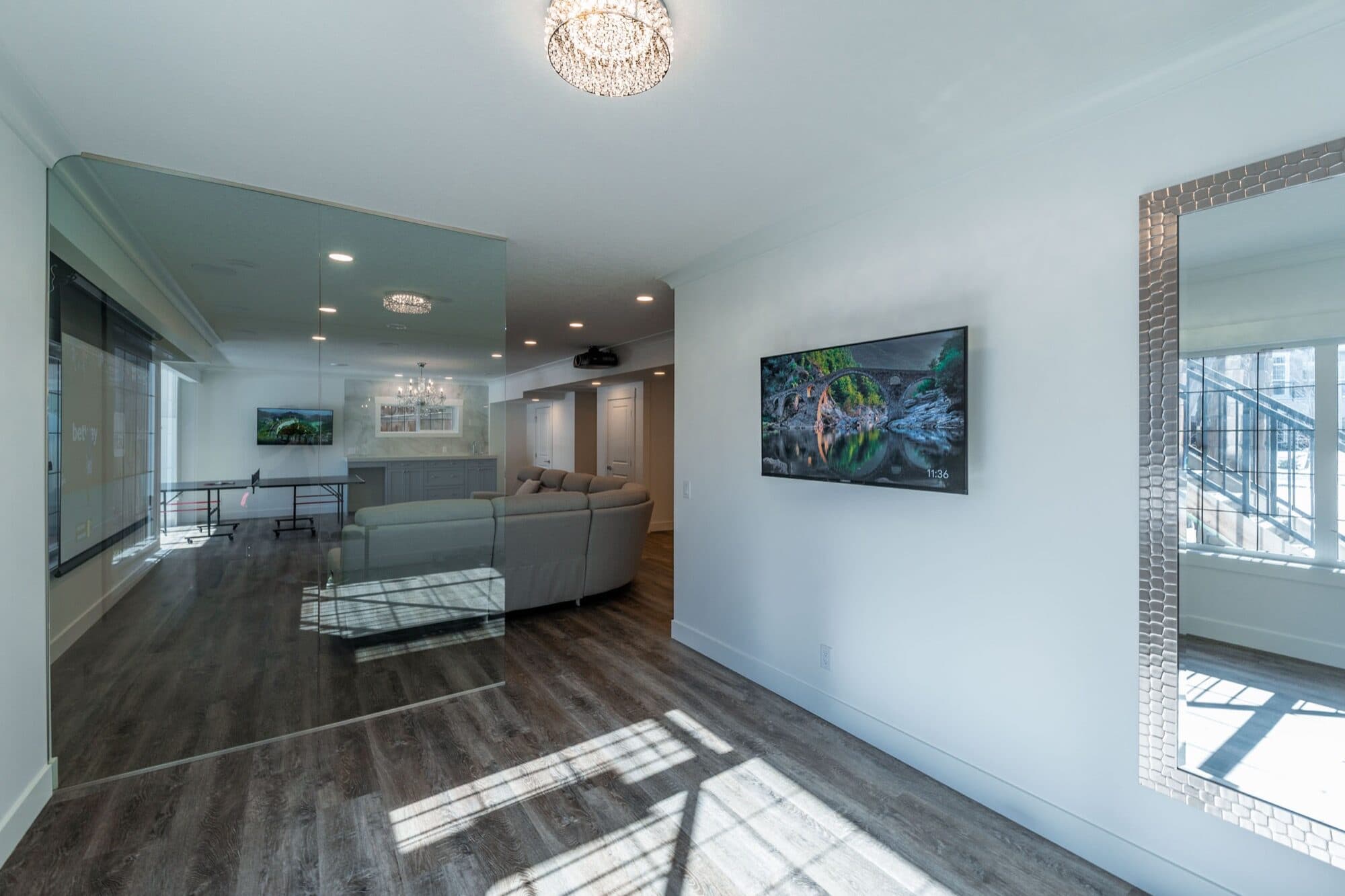 Basement rec room with gym visible through glass wall and TV