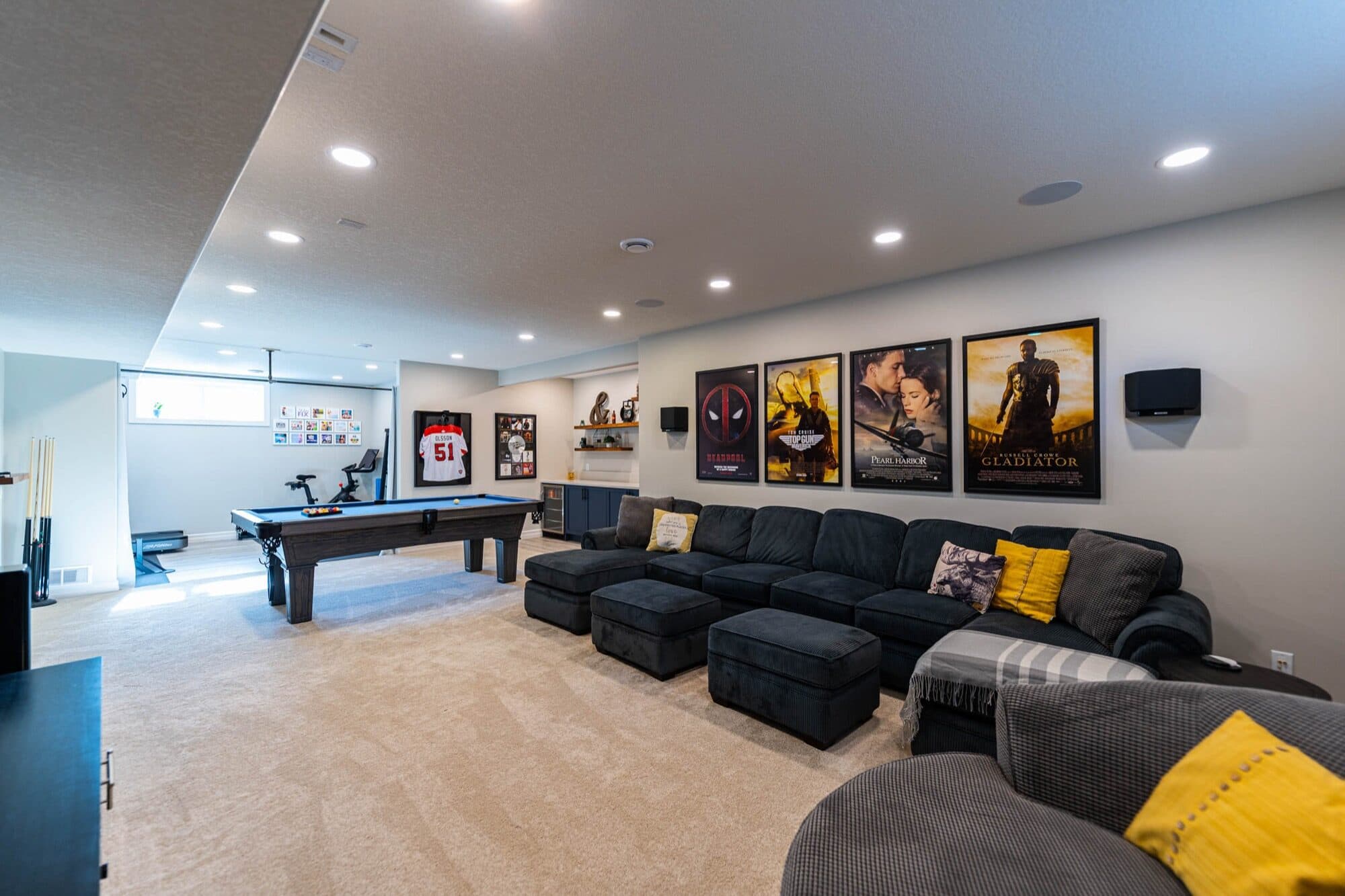 Basement rec room with movie posters and black sectional, wide angle