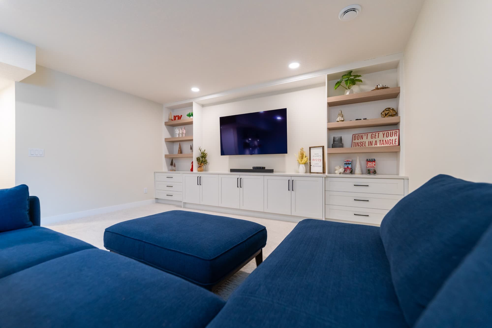 Basement rec room with navy sectional sofa and built-in wall unit