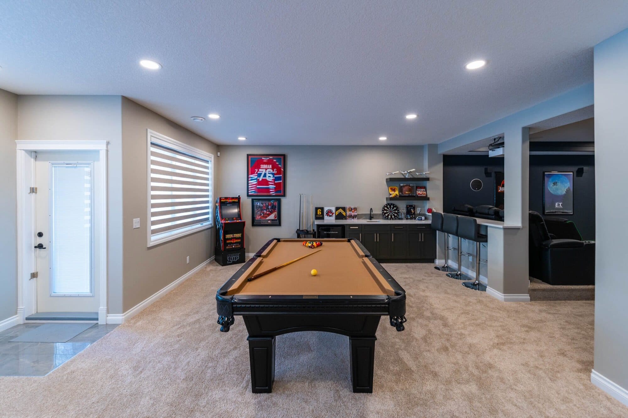 Basement rec room with pool table, arcade and bar seating area