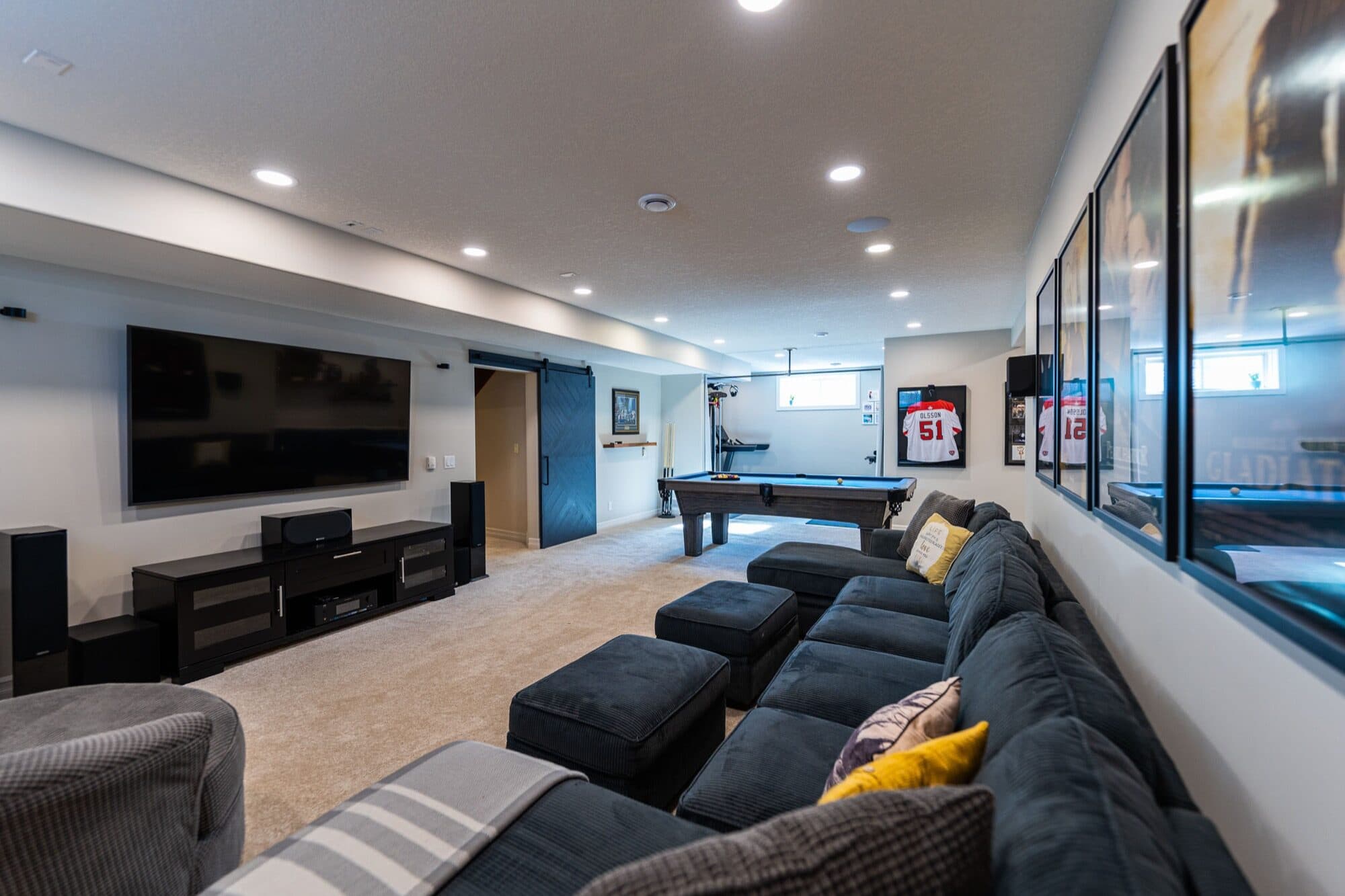 Basement rec room with pool table and TV wall, opposite angle