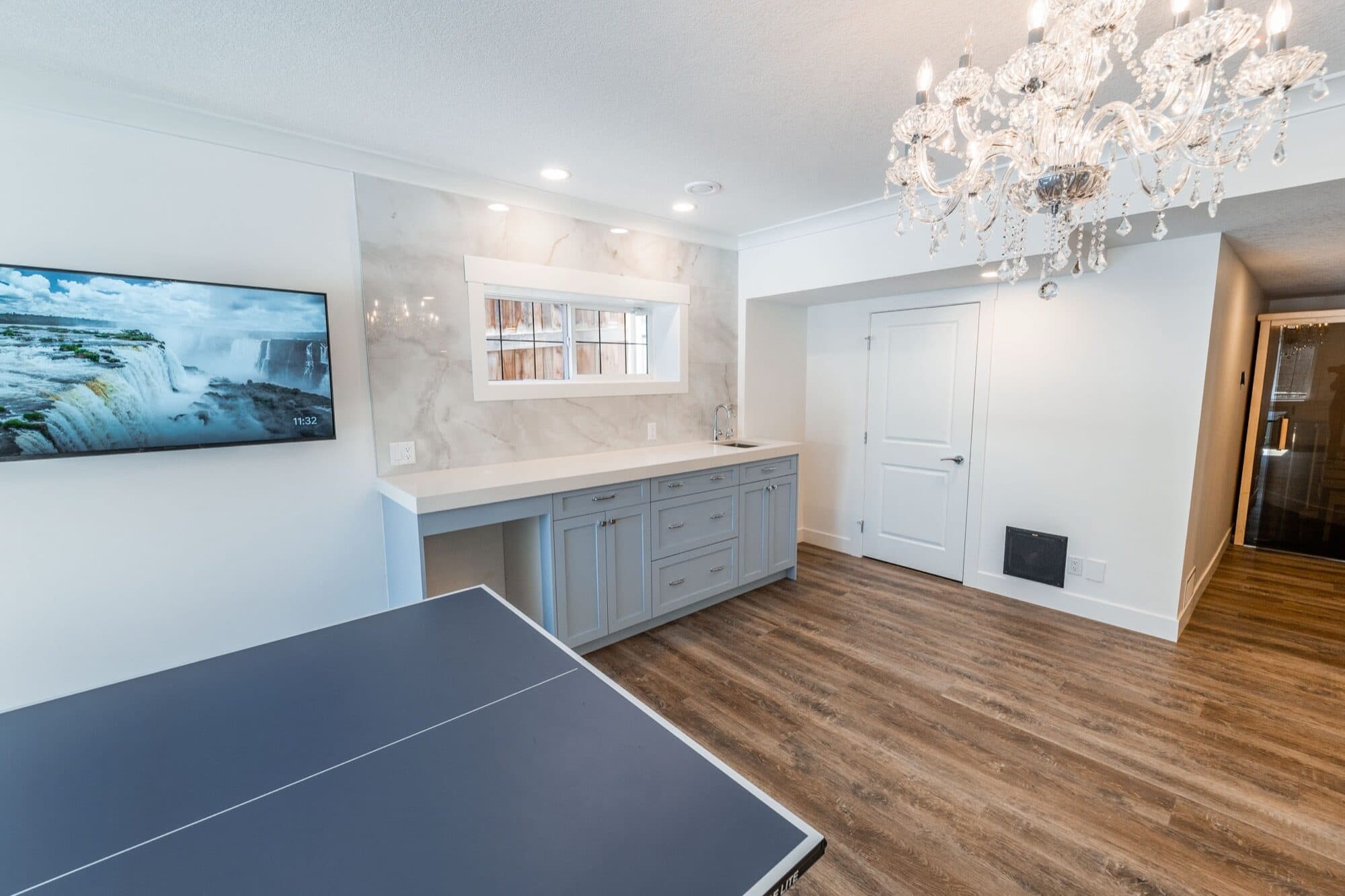 Basement rec room with projector screen, grey bar and sauna door
