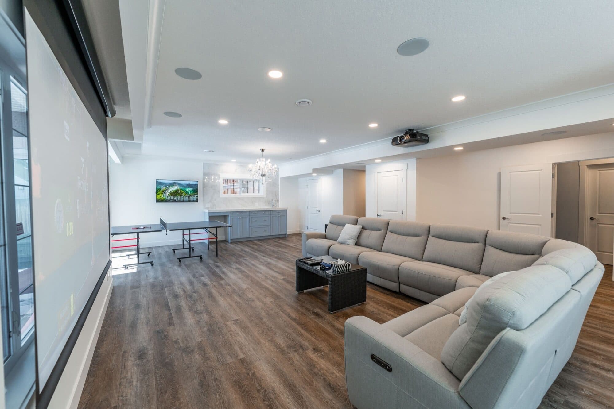 Basement rec room with projector screen, recliner and sectional, full view
