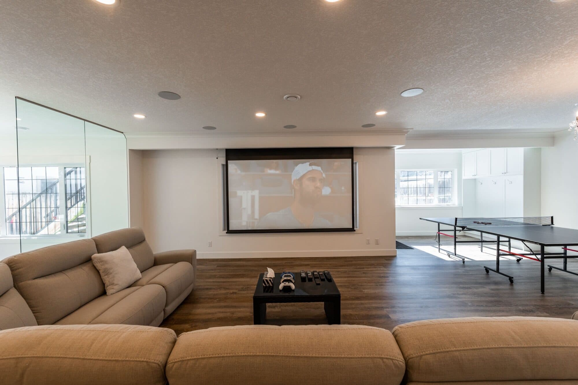 Basement rec room with projector screen, ping pong table and sectional