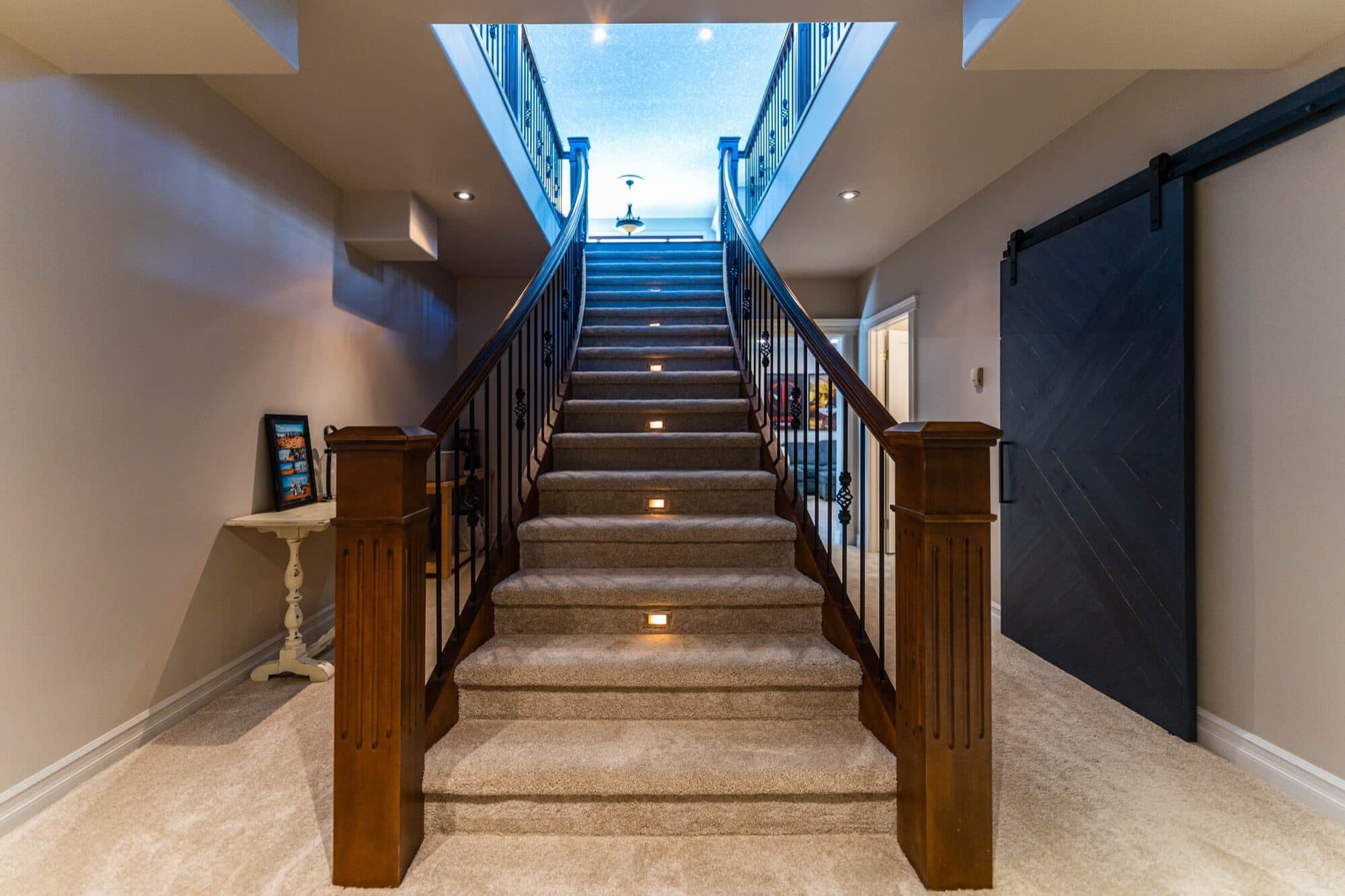 Basement staircase with lit treads, wood railing and barn door