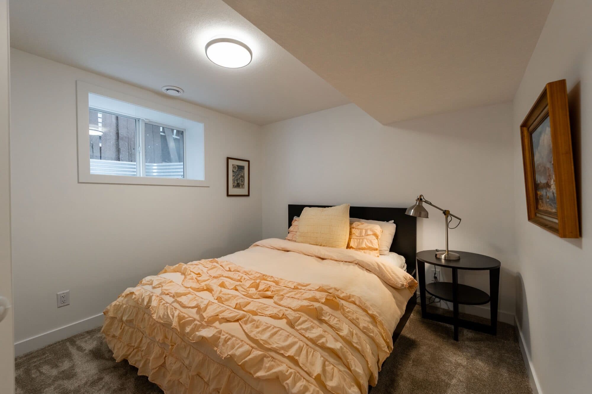 Legal suite basement bedroom with yellow bedding and egress window