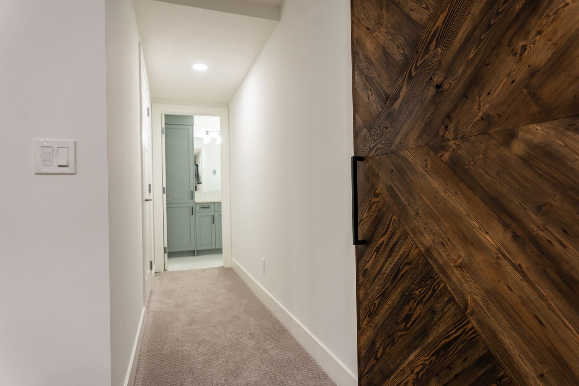 Custom chevron herringbone barn door in finished basement hallway