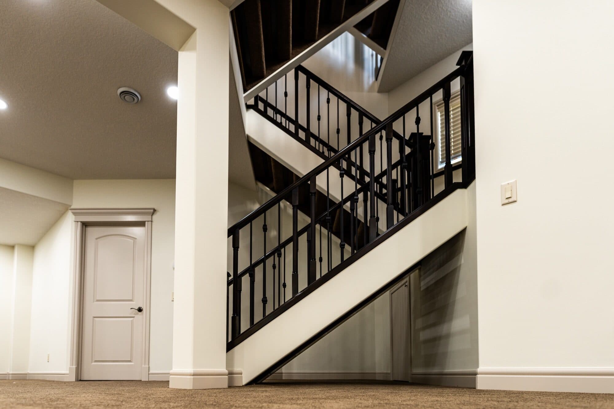 Grand curved staircase with wrought-iron spindles in finished basement