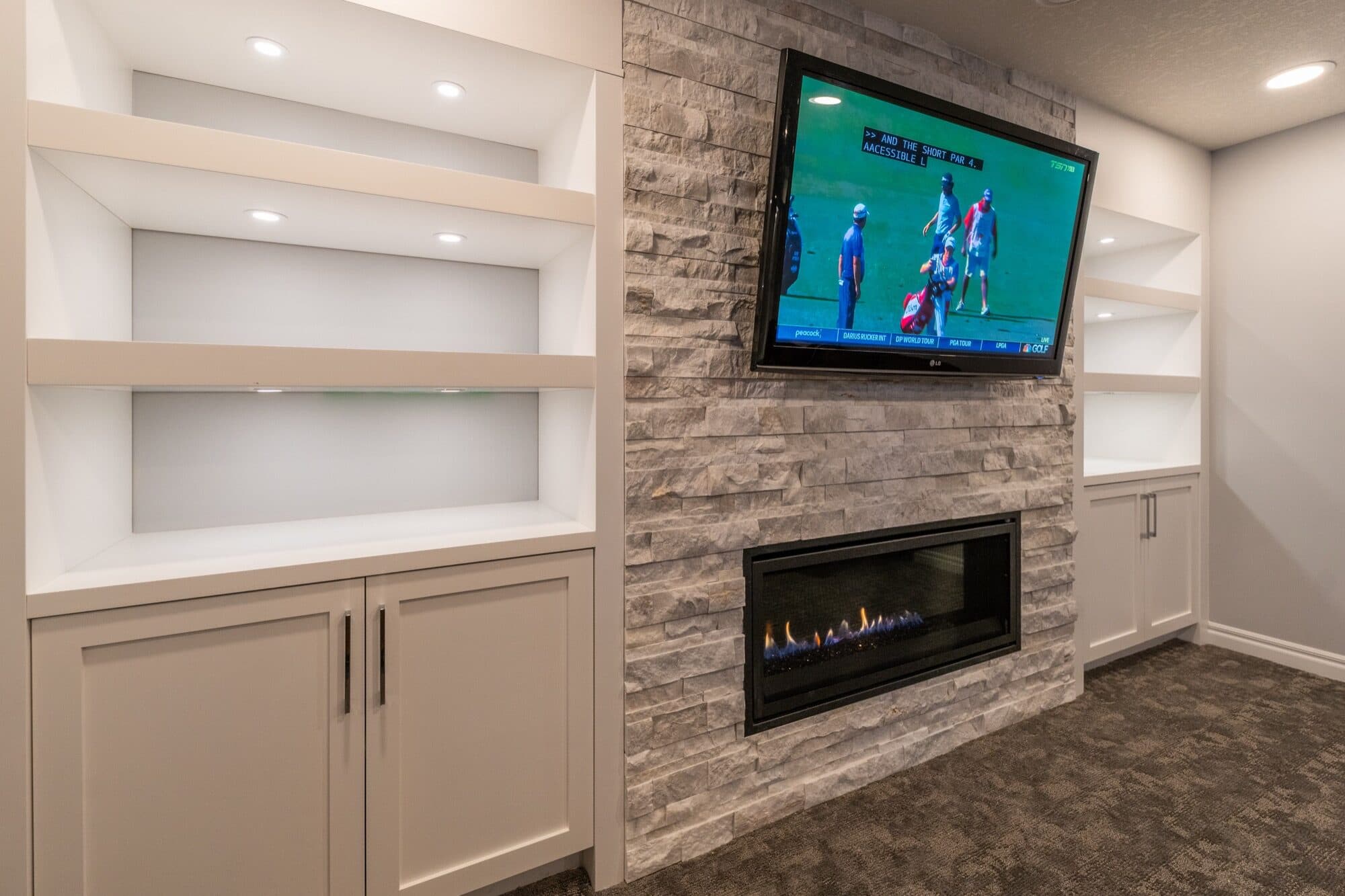 Stone fireplace with built-in shelves and lit niches in rec room