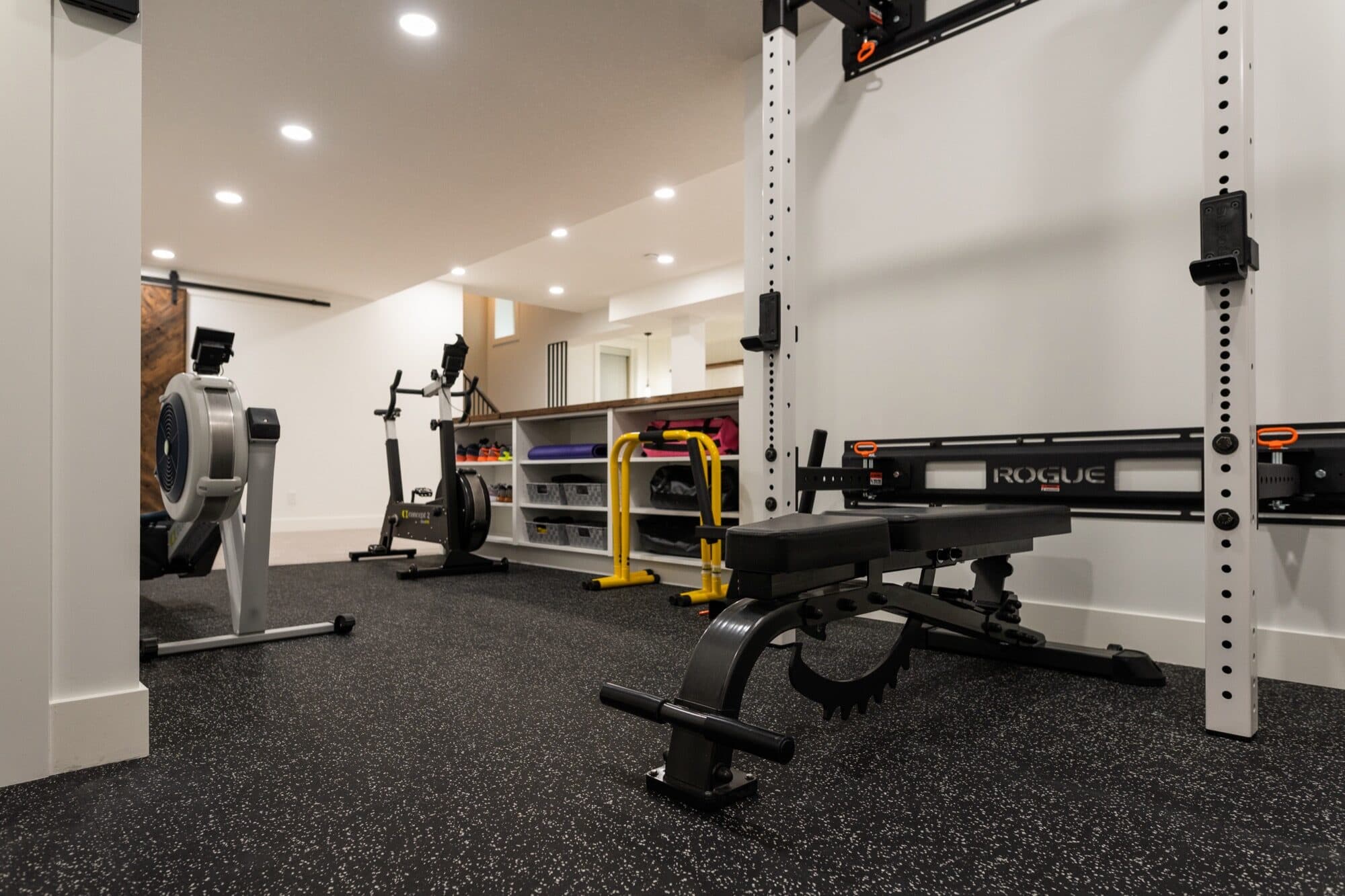 Basement home gym with power rack, rowing machine and rubber flooring