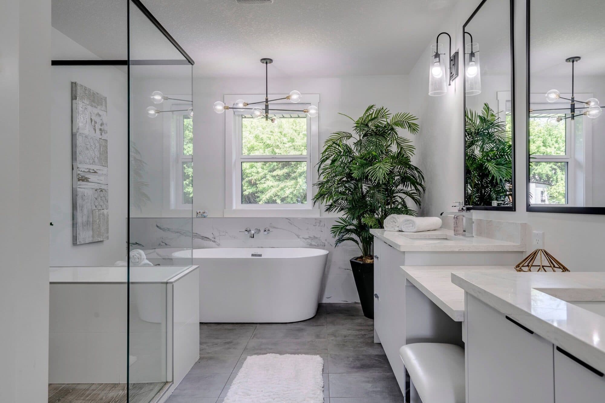Bright ensuite with freestanding tub, marble tile and plant