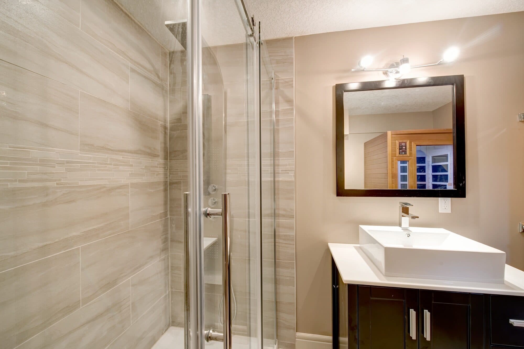 Basement bathroom with glass shower, vessel sink and wood vanity