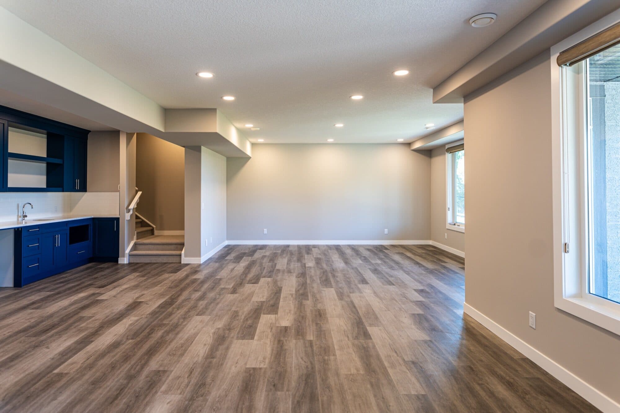 Open basement with blue cabinets and wide rec room space