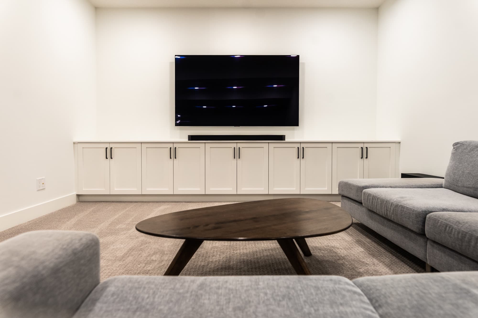 Bright basement rec room with built-in TV cabinet and sectional sofa