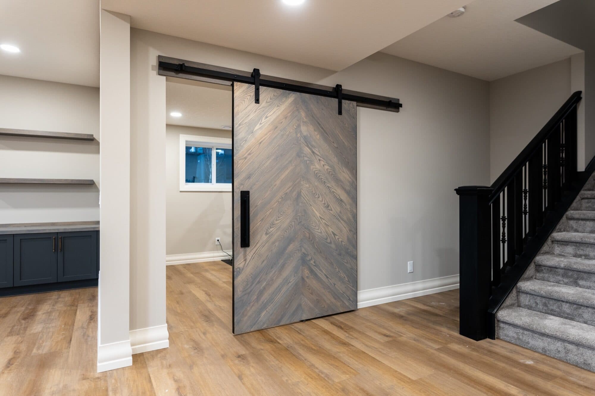 Chevron barn door detail with staircase and rec room beyond