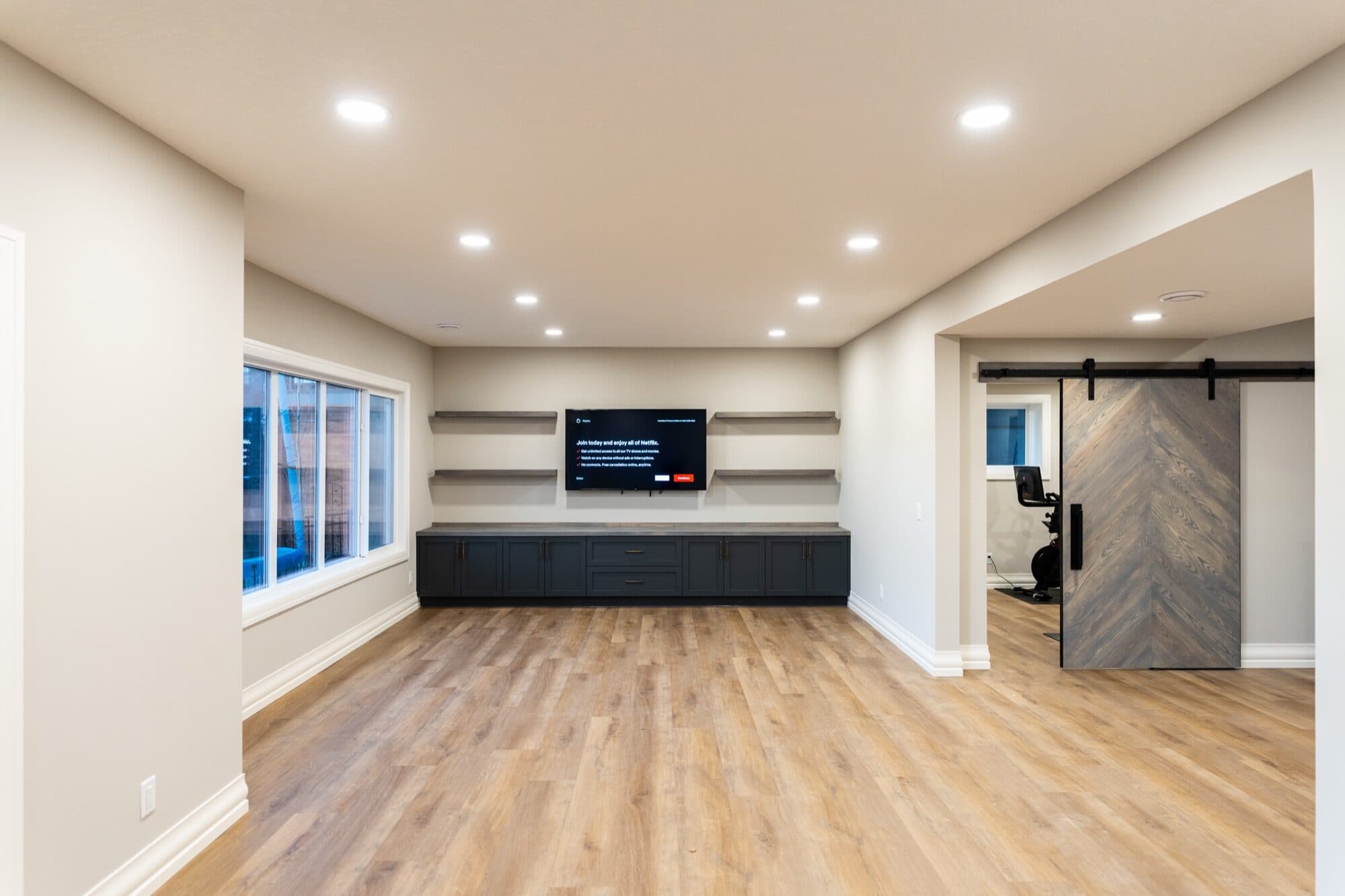Basement living room with built-in console and herringbone barn door
