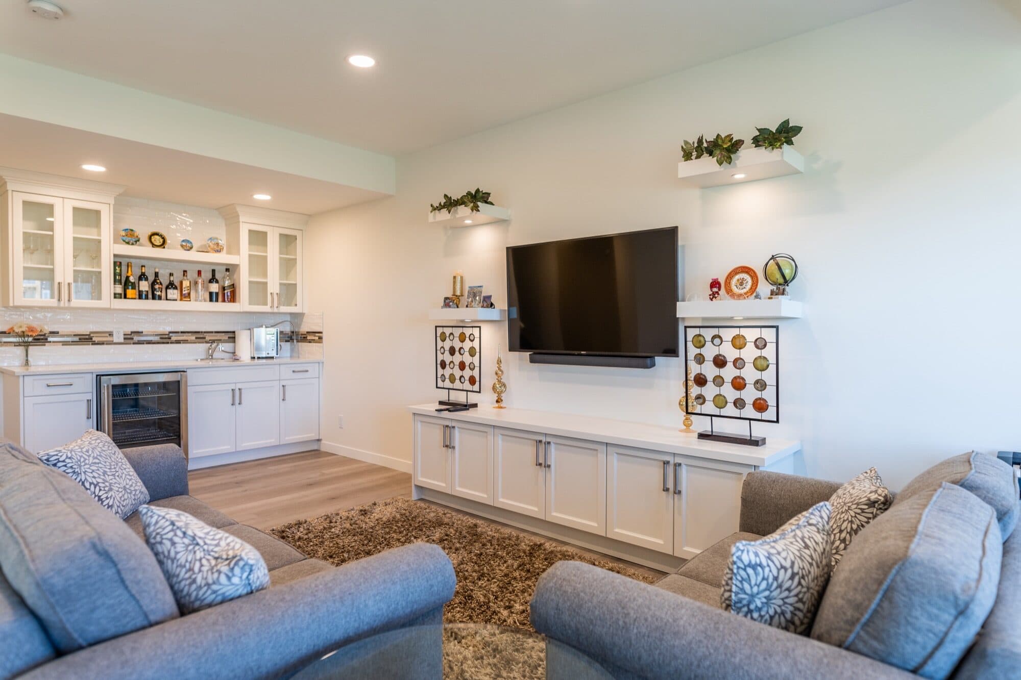 Bright open-concept basement rec room with white built-ins and bar