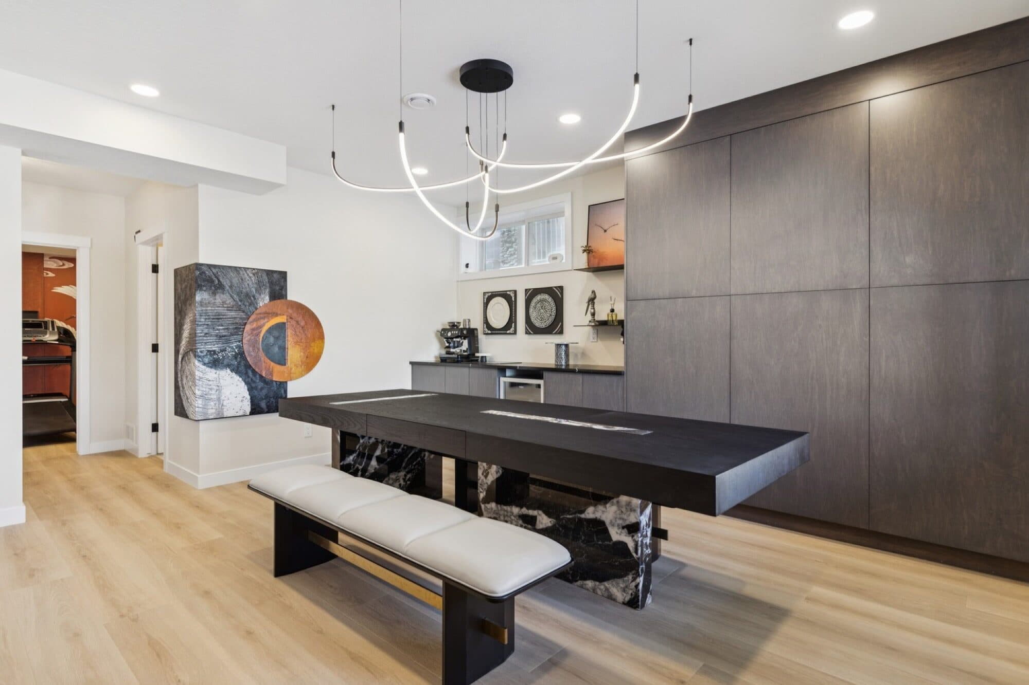 Basement entertaining space with marble dining table and view to the gym hallway