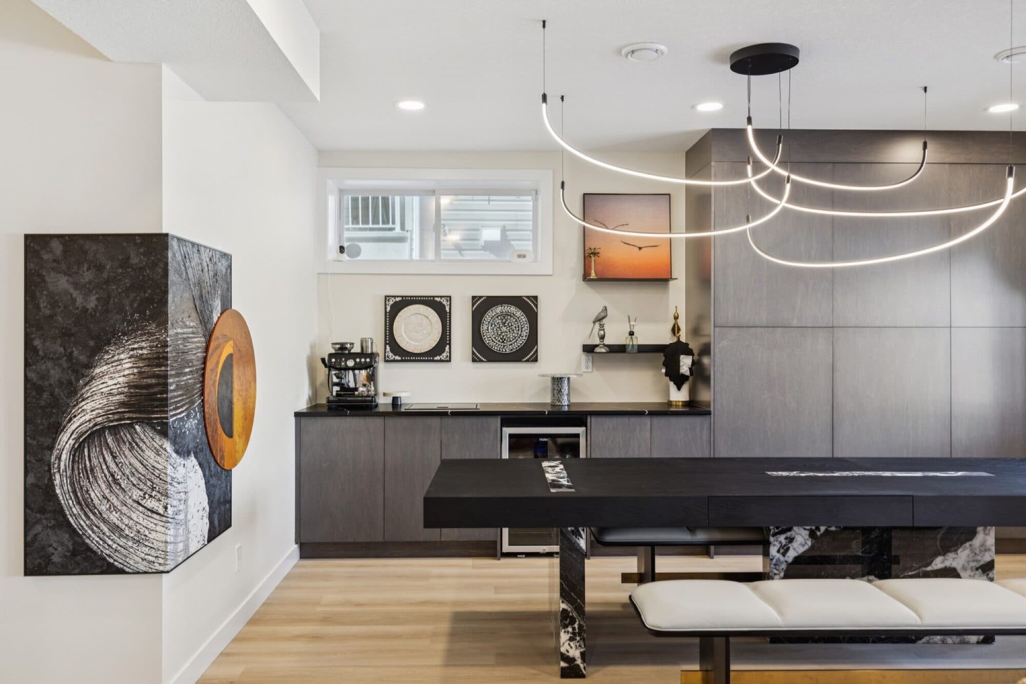 Basement entertaining room with coffee bar, sculptural art wall and marble dining table