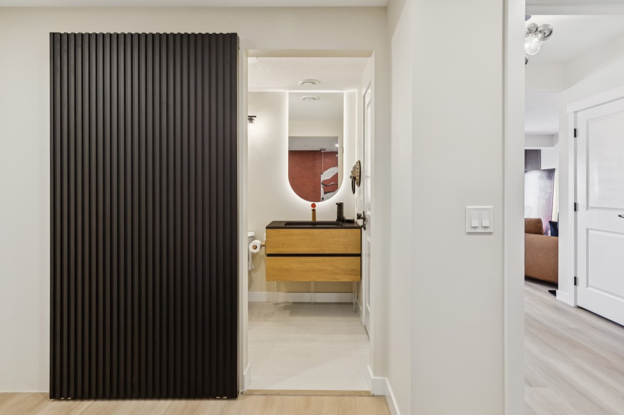 Basement hallway with black slat feature wall leading to a powder room