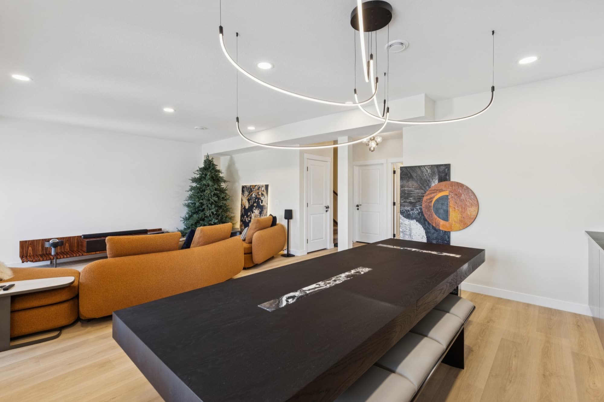 Basement living room with curved orange sofas beside a black-marble dining table