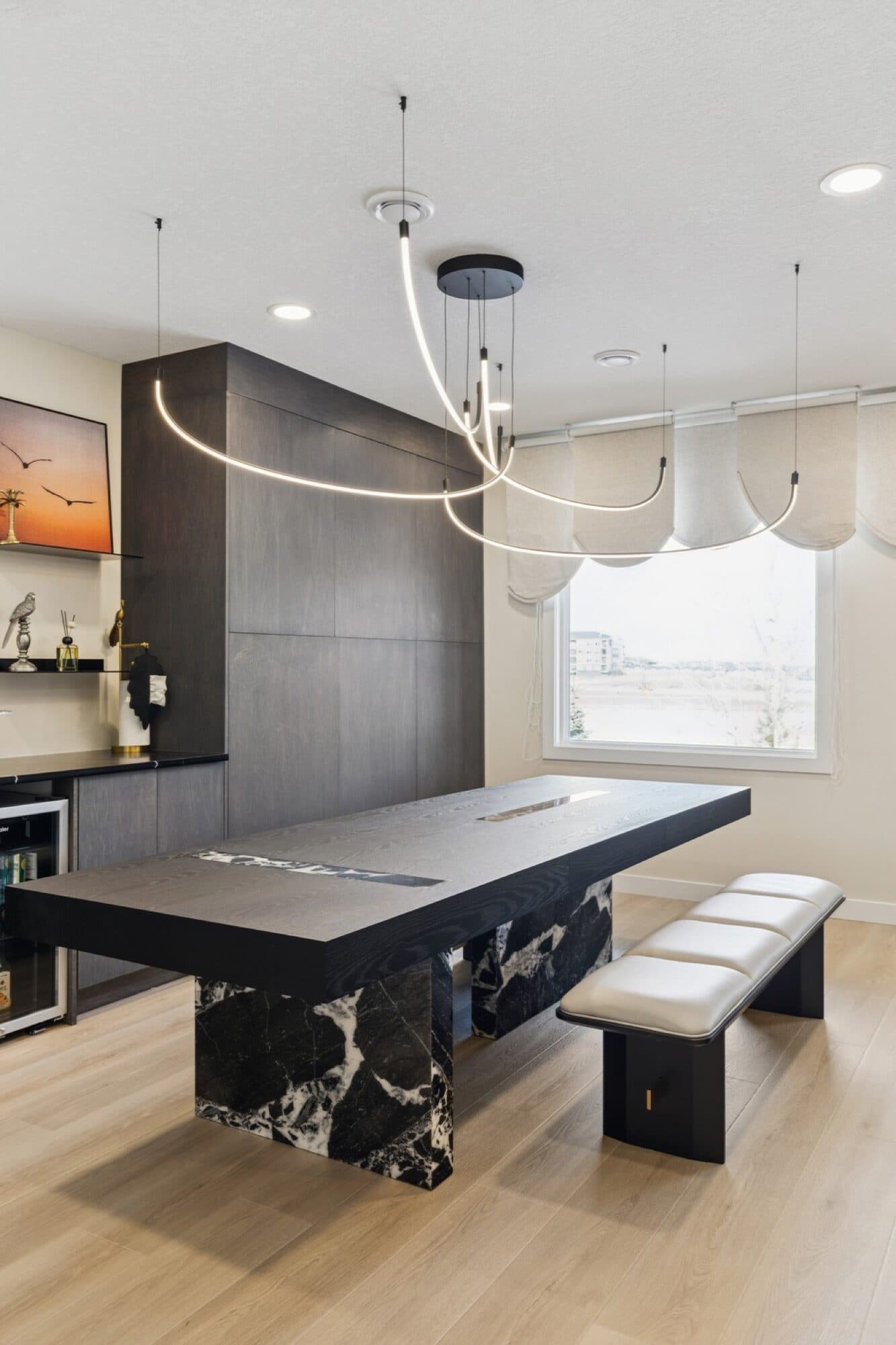 Basement black-marble dining table with curved LED chandelier and wood feature wall