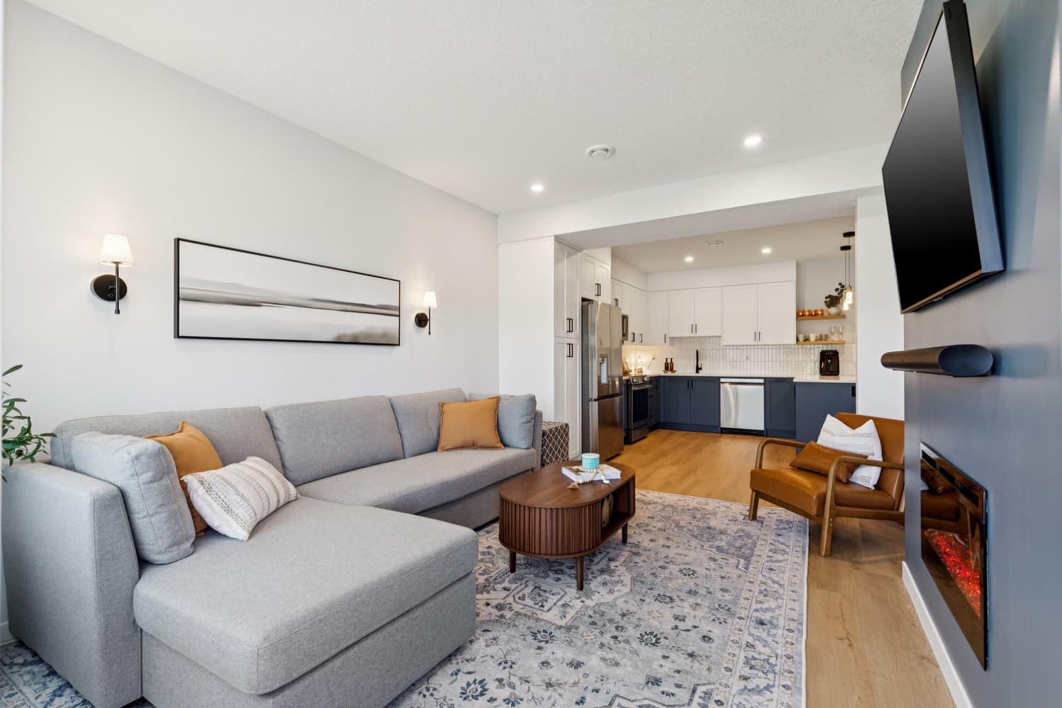 Open-plan legal suite living room with sectional sofa and kitchen beyond