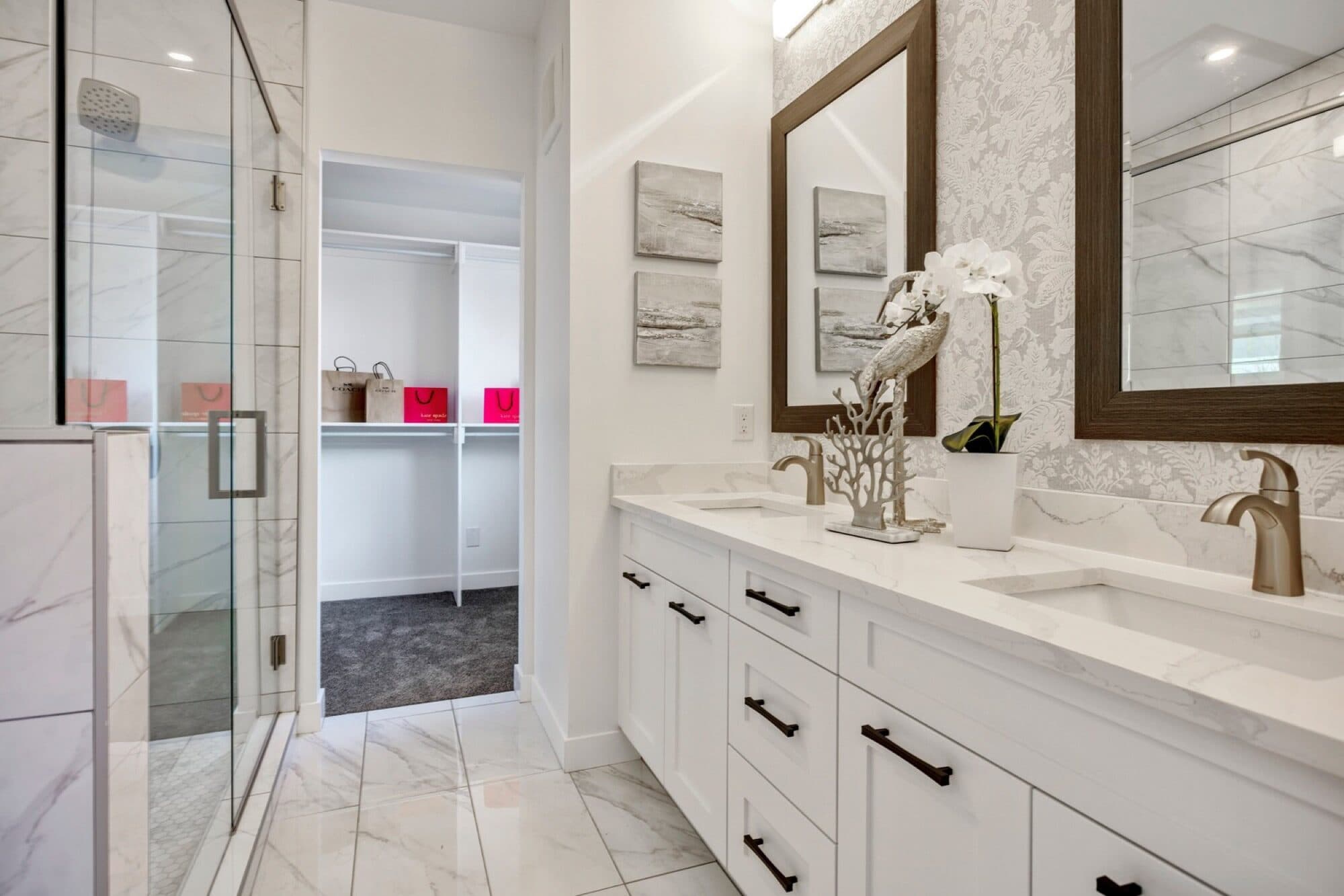 Ensuite with double vanity, marble tile and walk-in closet view