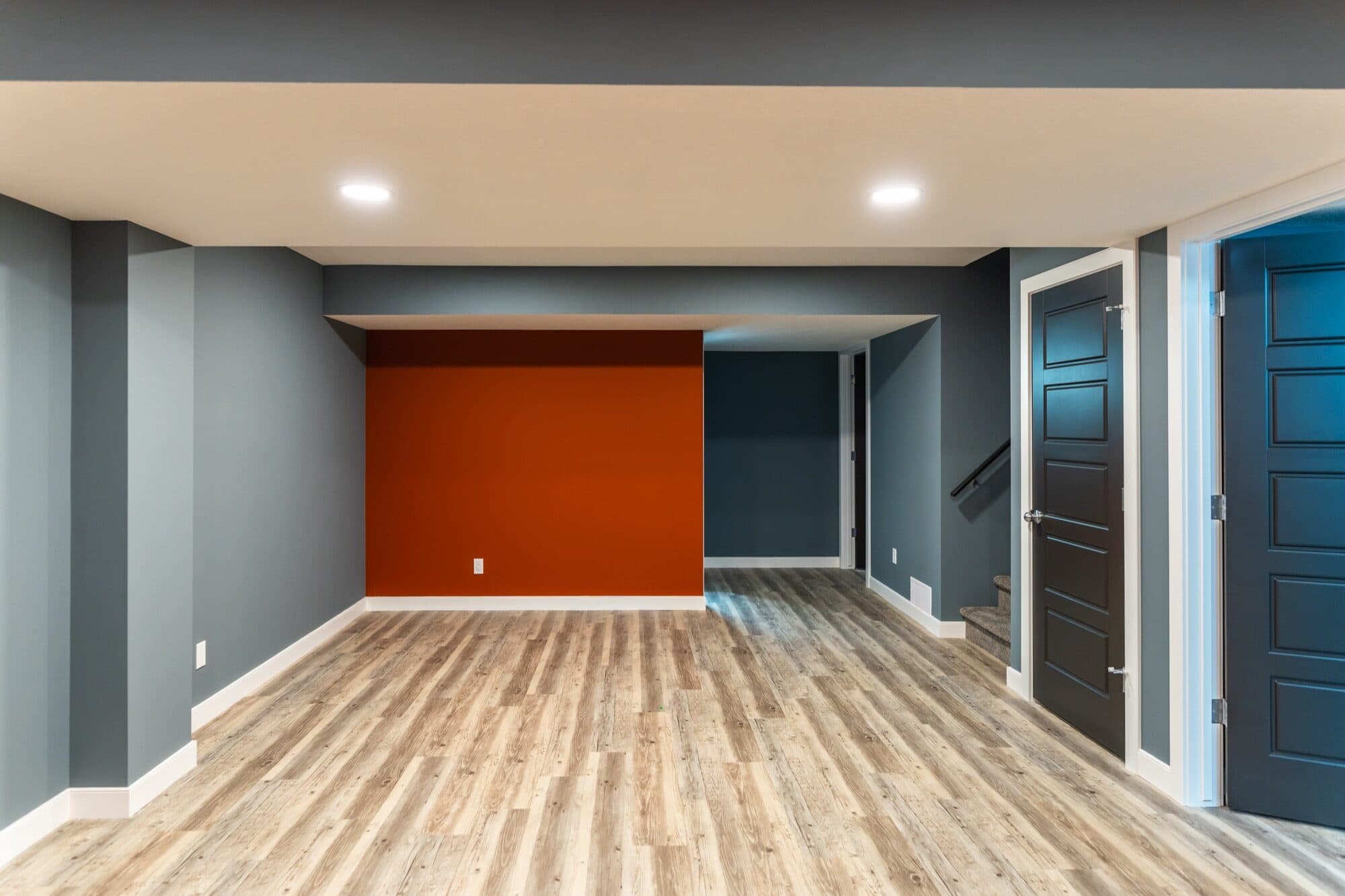 Finished basement interior with accent wall and wide-plank flooring
