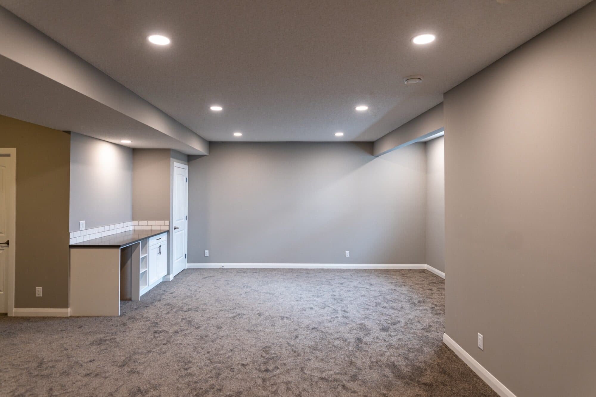 Open basement rec space with carpet and partial wet bar view