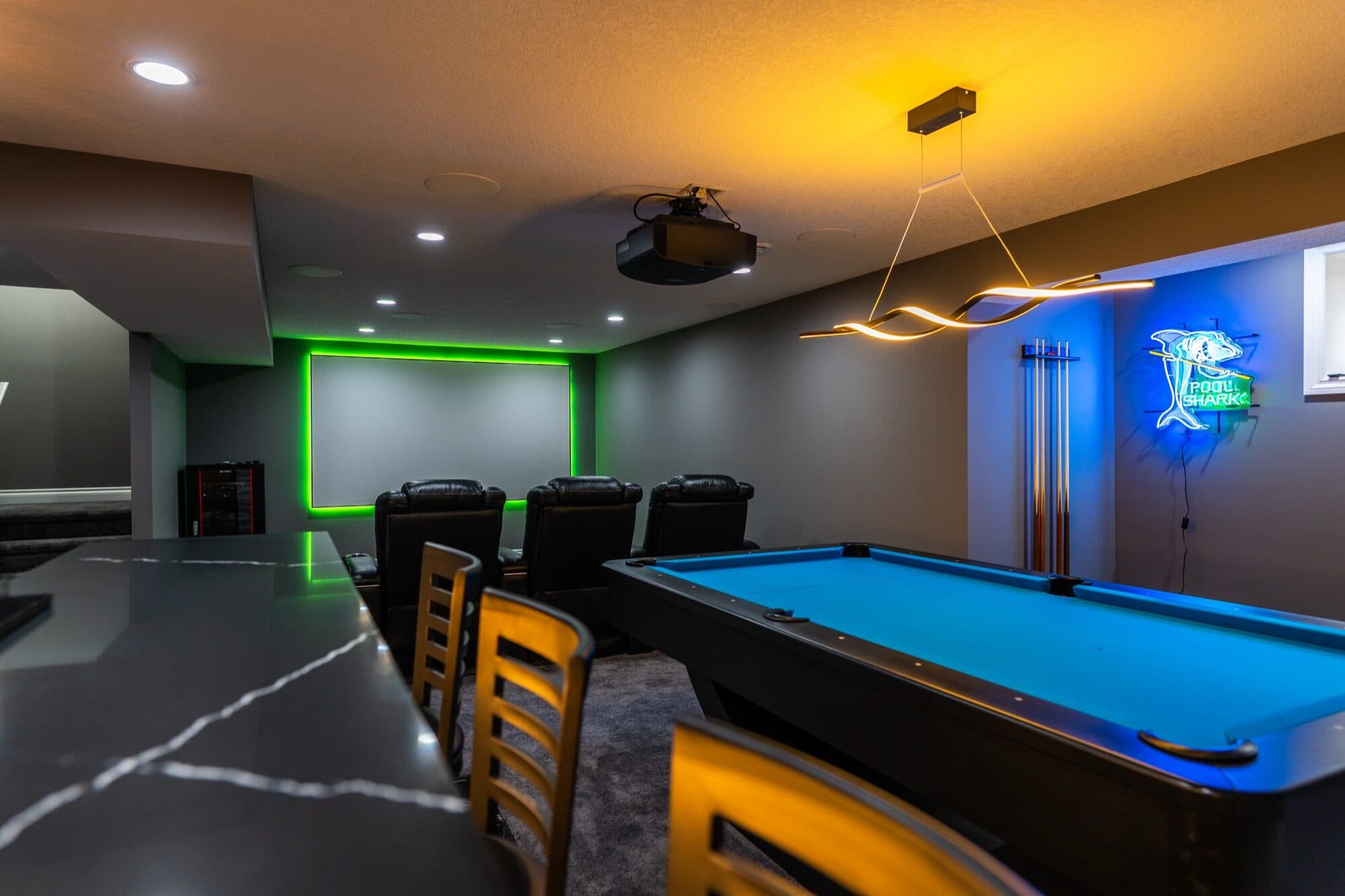 Basement entertainment room with pool table, neon sign and theatre screen