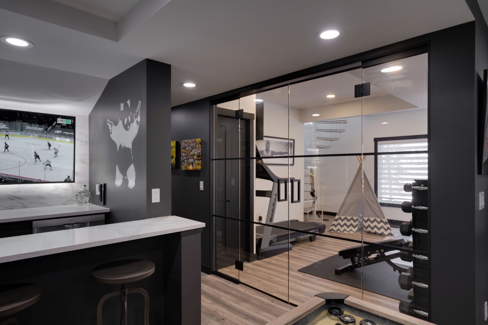 Basement bar area with glass-enclosed gym behind